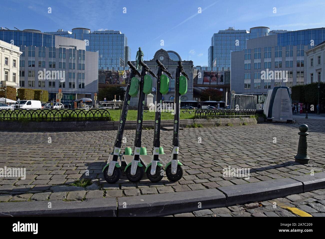 A row of Lime S dockless electric hire scooters in Place De Luxembourg, Brussels with the European Parliament buildings in the background Stock Photo