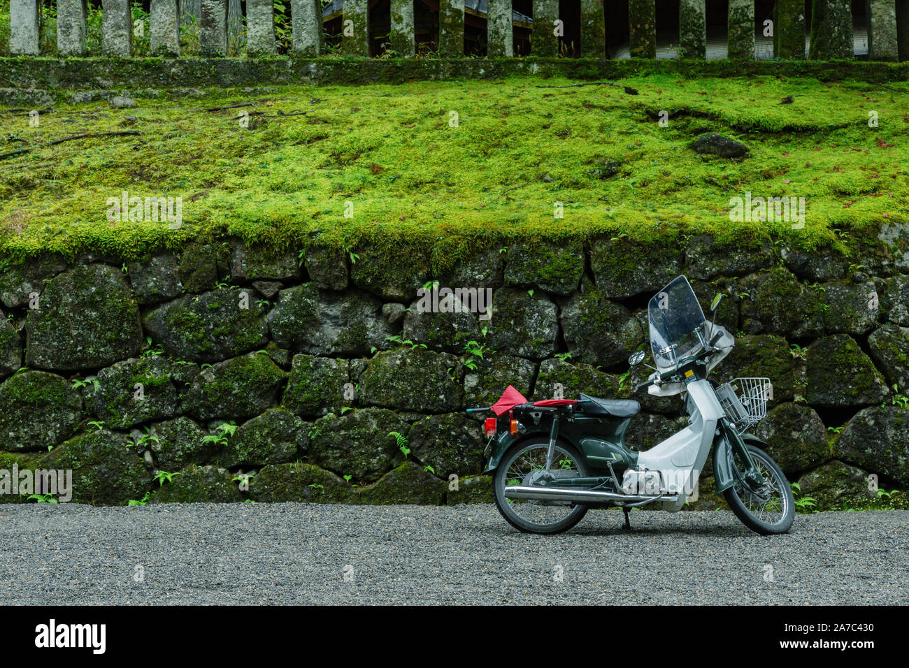 vintage old model japan motorcycle parking in the park with beautiful rock wall and grass in Tokyo city, Japan. vintage motorbike parking in the garde Stock Photo