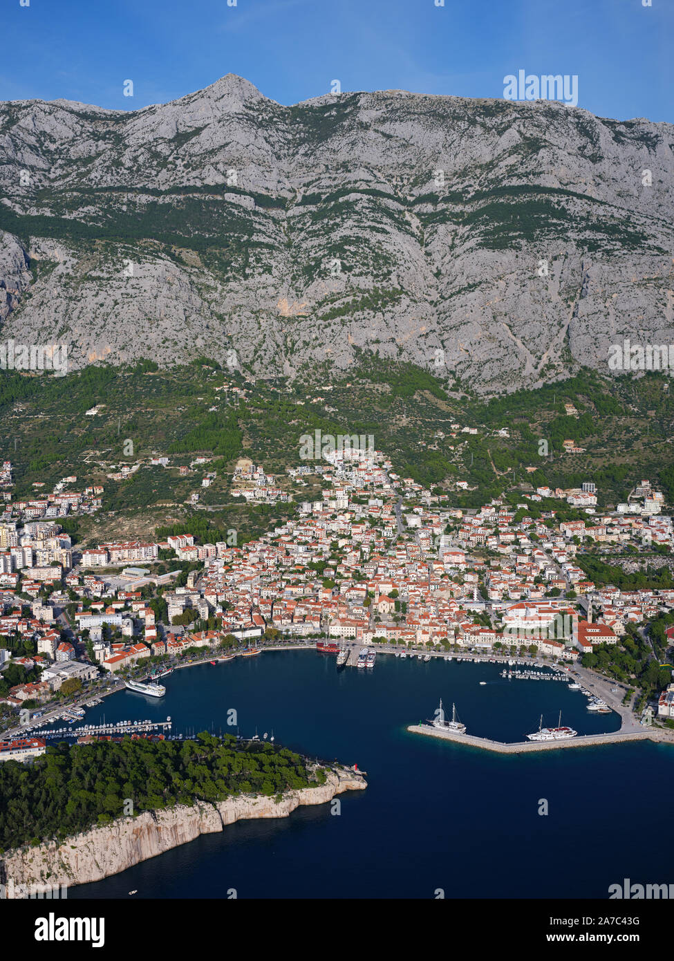 AERIAL VIEW. Seaside resort at the foothill of a 1400-meter-high mountain. Makarska, Dalmatia, Croatia. Stock Photo