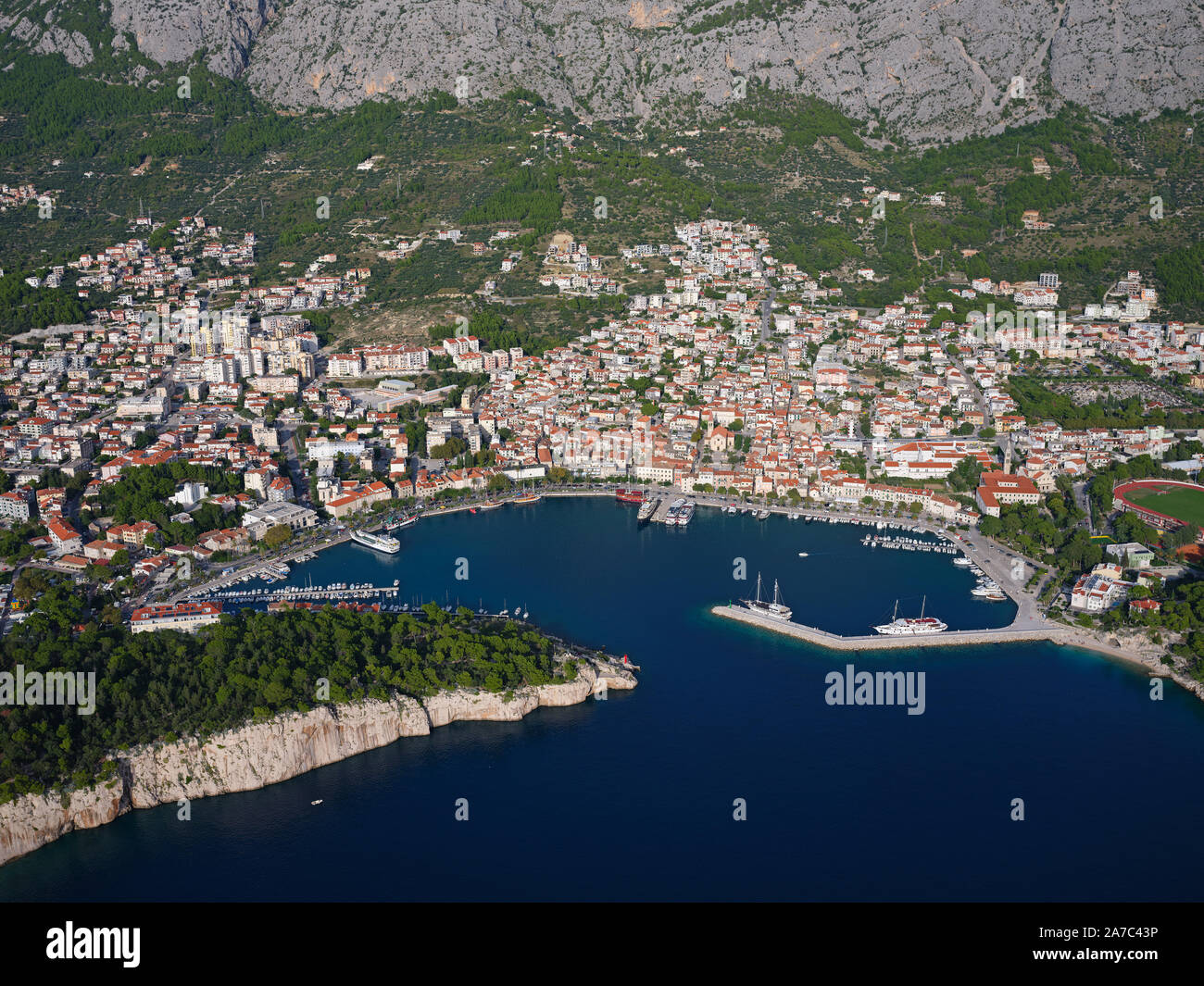 AERIAL VIEW. Picturesque seaside resort with its sheltered rocky bay. Makarska, Dalmatia, Croatia. Stock Photo