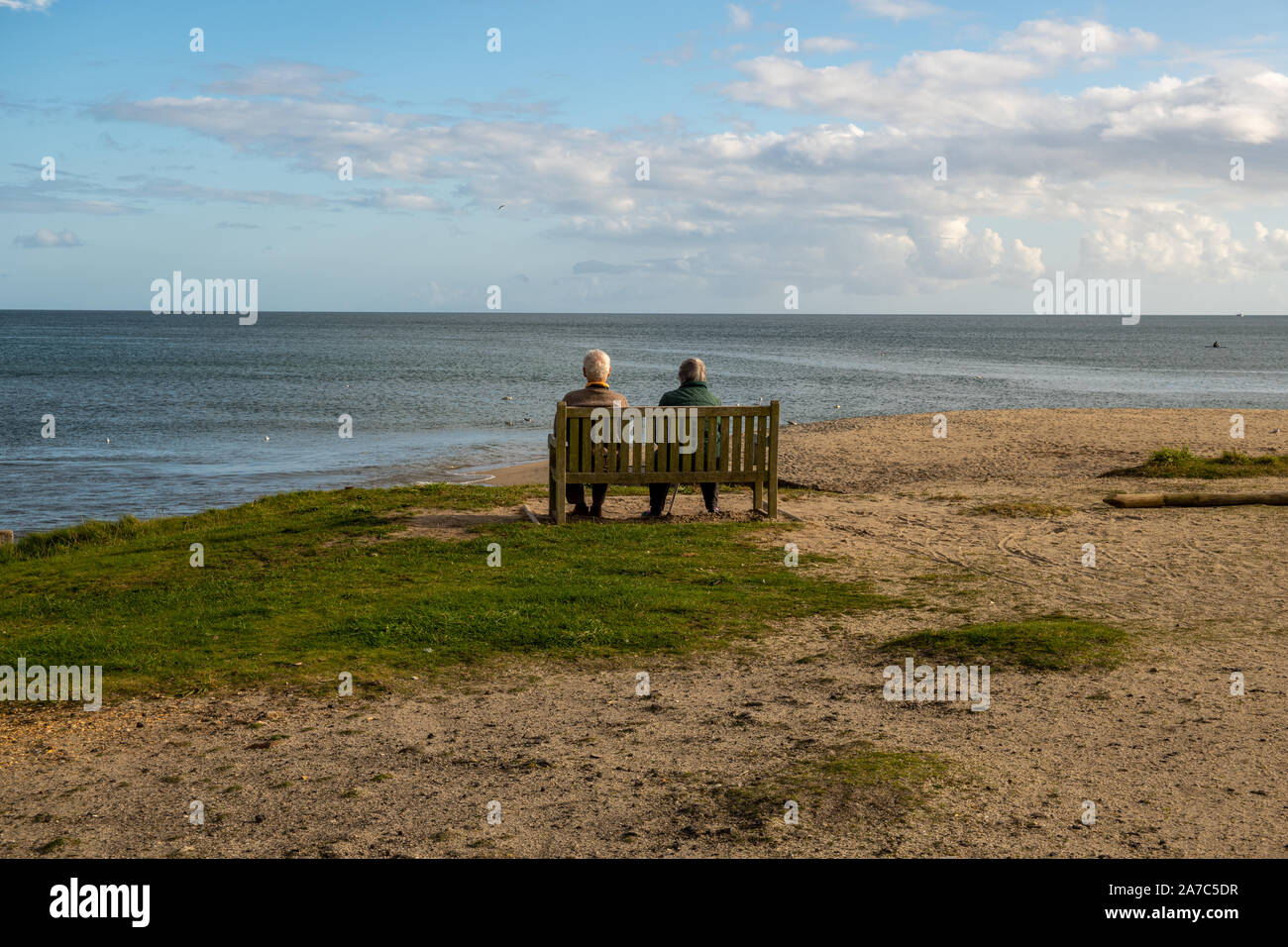 Old couple sitting on a beach bench overlooking the sea Stock Photo - Alamy