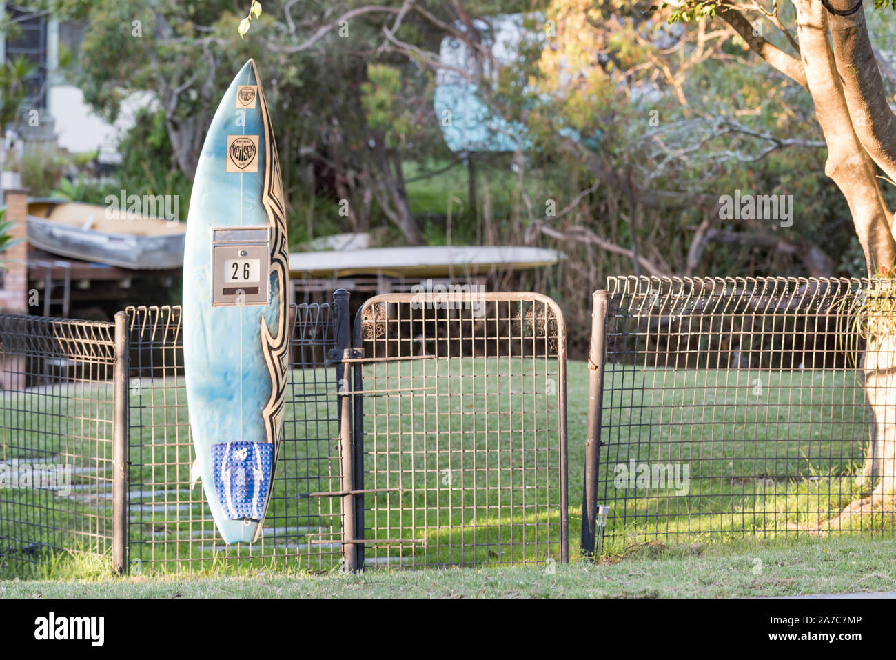 A letterbox fashioned from a converted upcycled surfboard attached to a steel fence in the southern Sydney suburb of Bundeena in Australia Stock Photo