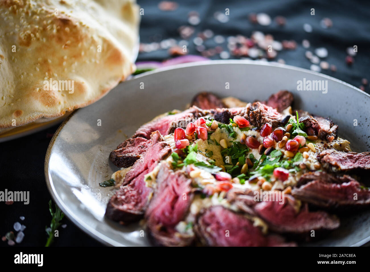 lebanese hummus dish with roasted beef & pomegranate seeds Stock Photo