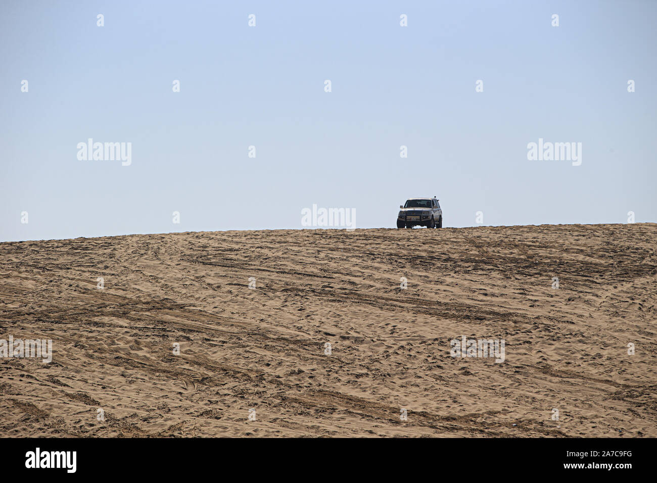 A lone four wheel drive perched at the top of a dune at Sealine Shore south of Doha, Qatar. Stock Photo