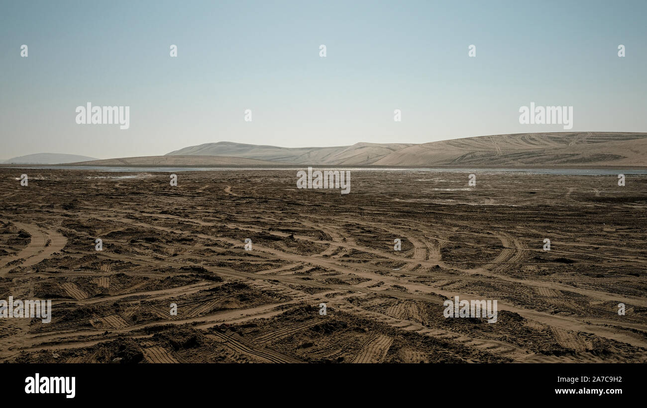 Four wheel drive tracks covers the vast sandy desert Sealine Beach of Qatar near Doha where thrill seekers come dune bashing. Stock Photo