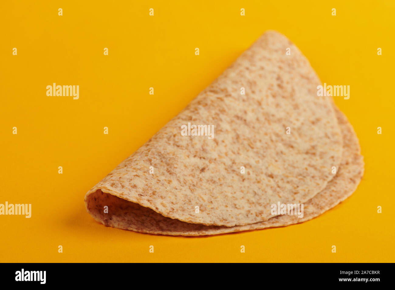 One empty folded tortilla isolated on yellow background side view Stock Photo