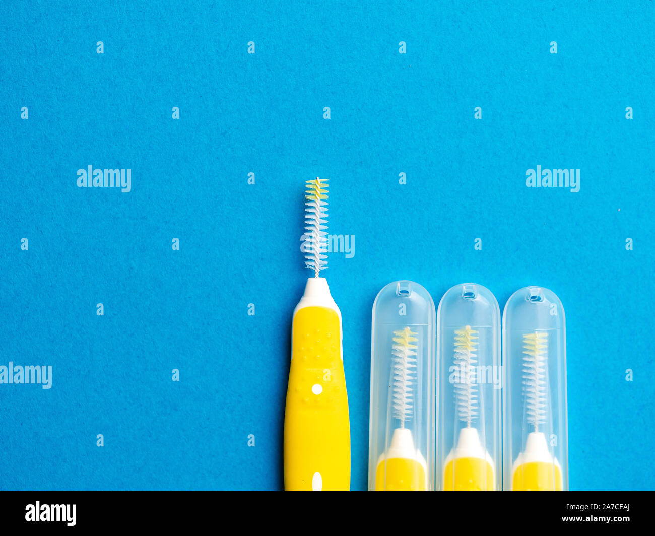 Interdental brush for interdental spaces over blue background with copy