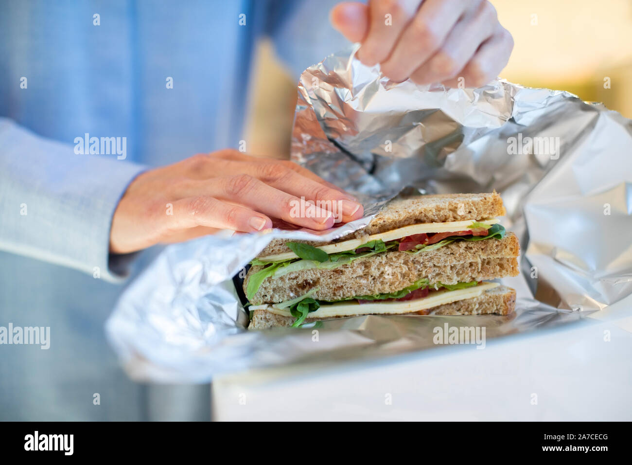 Close Up Of Woman Wrapping Sandwich In Non Reusable Aluminium Foil Stock Photo