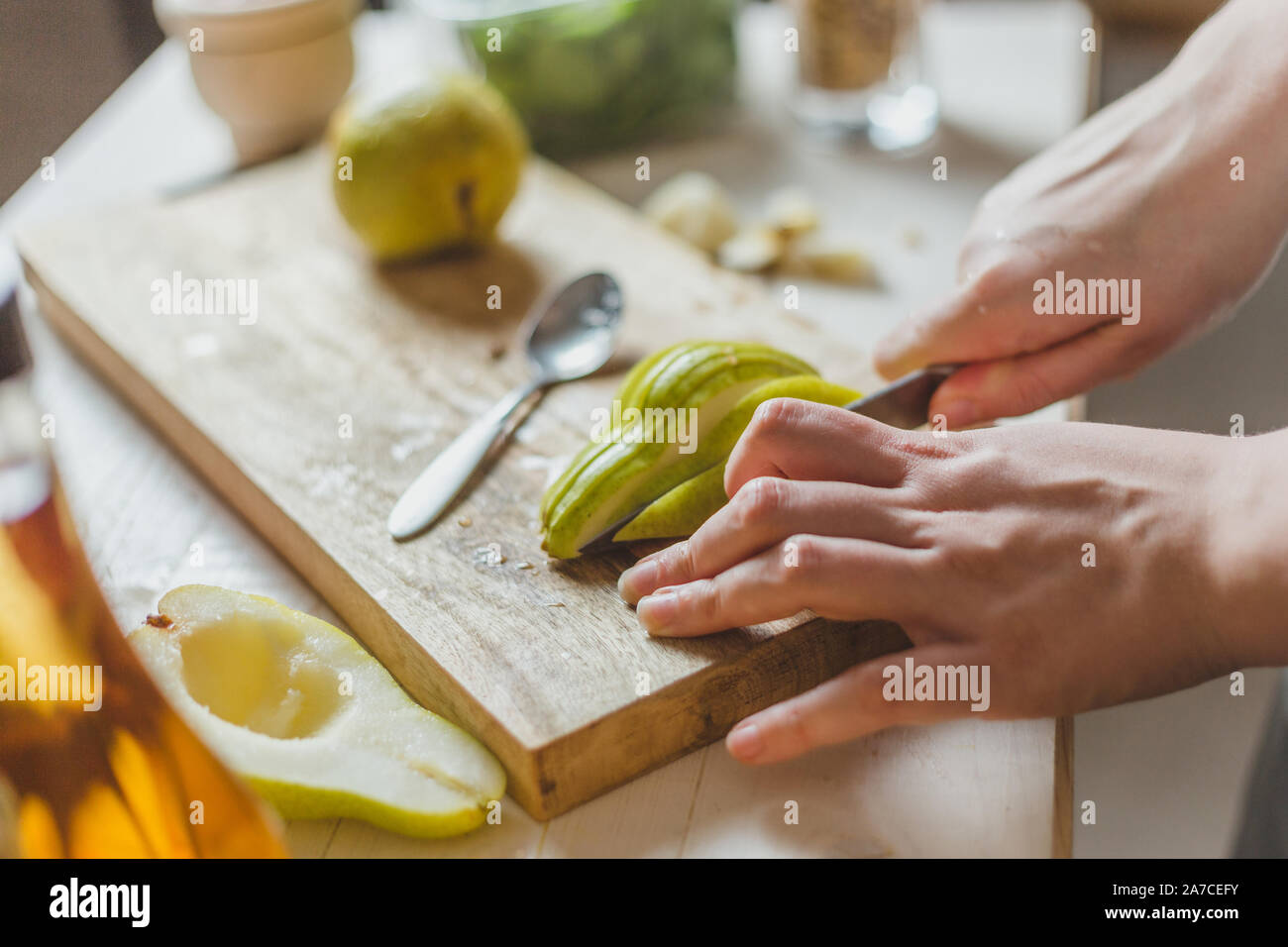 Slicing pears in a salad on a wooden board - homemade recipe - housewife's hands - rural Stock Photo