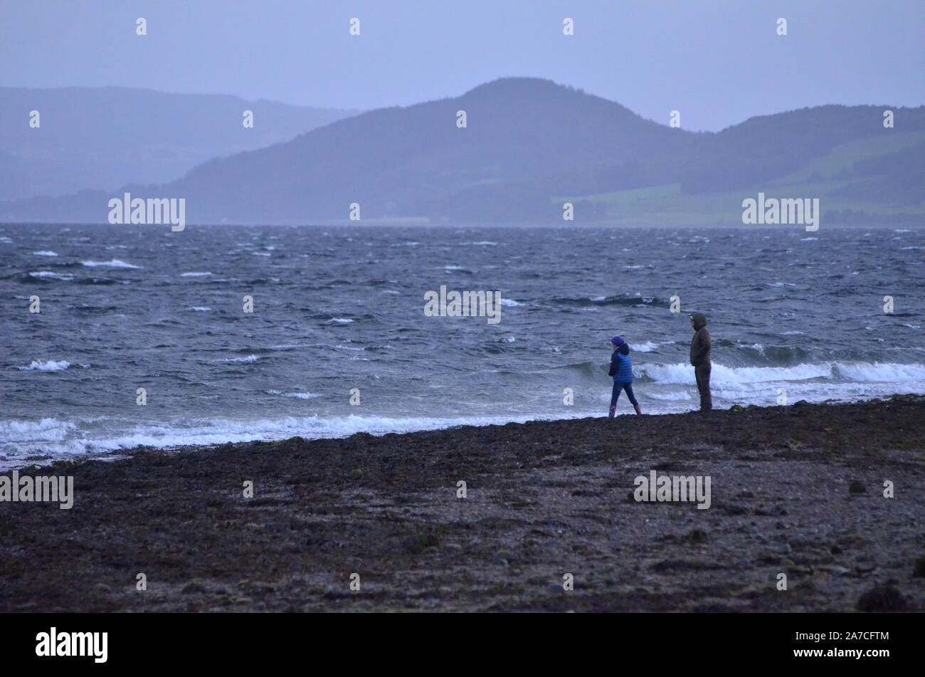 Two people on the beach at Channonry Point on the Black Isle  in the Moray Firth of the Scottish Highlands Scotland UK Stock Photo