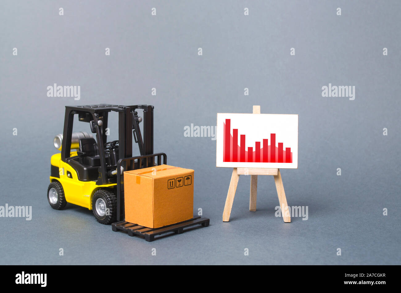 Forklift truck carries a cardboard box near a stand with a Negative red trend chart. decline in the production of goods and products, the economic dow Stock Photo