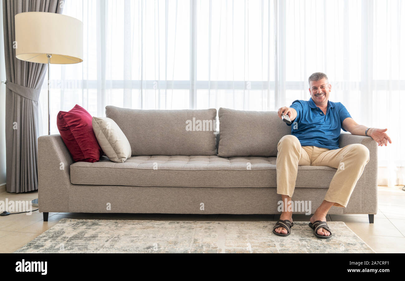 middle aged man sitting on a sofa and watching TV Stock Photo