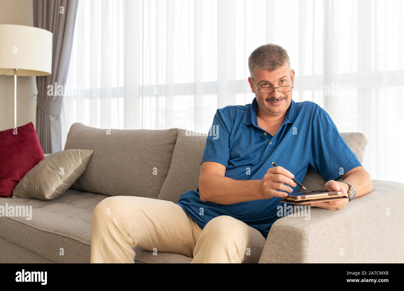 middle aged man working on his tablet on a sofa Stock Photo