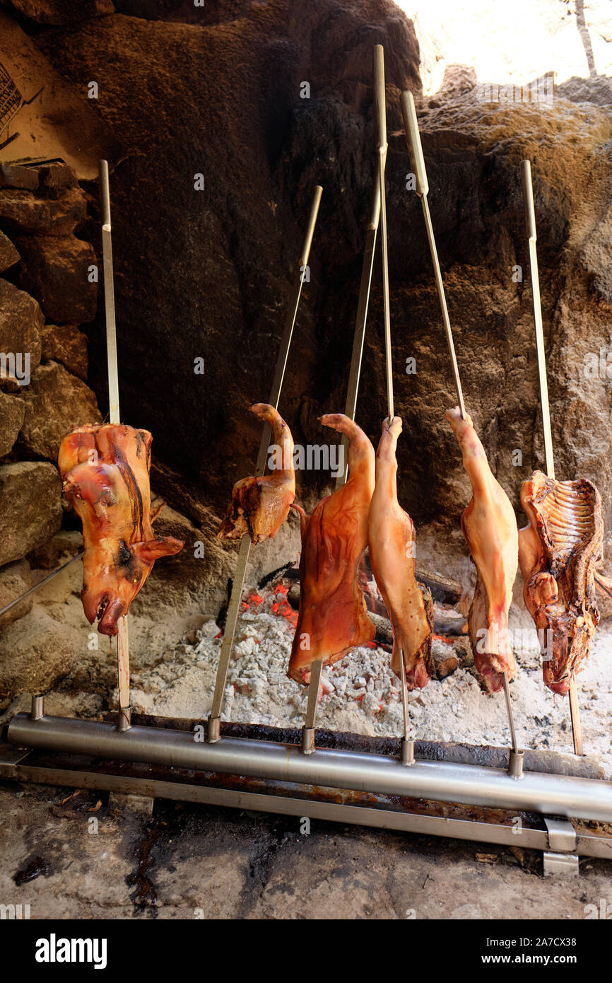 An open fire roast suckling pig cooked on a spit in sections at a typical rustic family run agriturismo in Sardinia Italy Europe Stock Photo