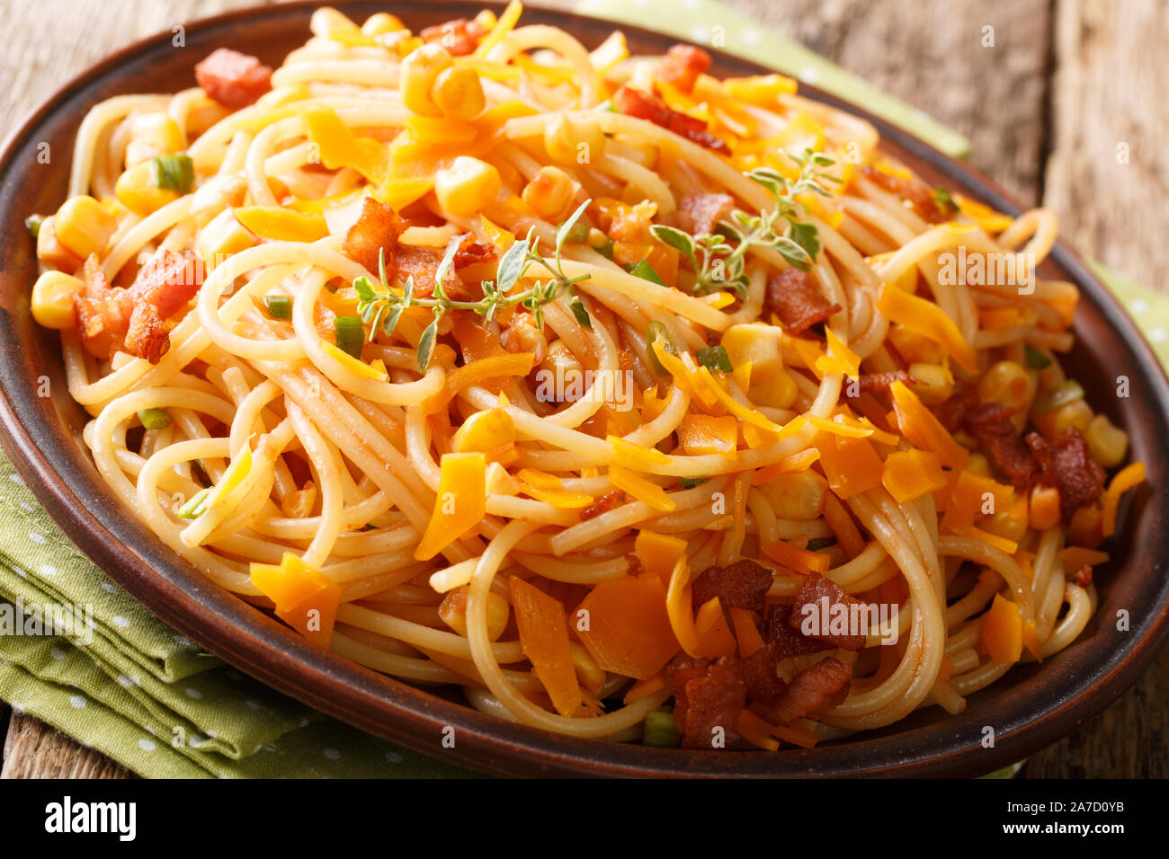 Hot Italian spaghetti with bacon, corn and Mimolette cheese close-up on a plate on the table. horizontal Stock Photo