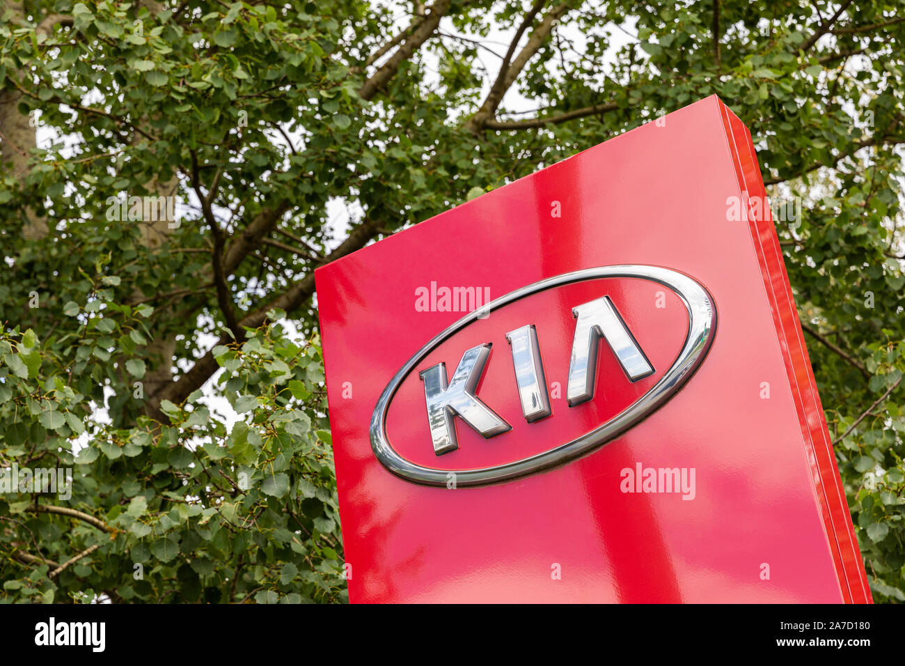 Minsk, Belarus - July 15, 2019: KIA logo Kia dealership sign against green leaves on trees. Kia is South Korea's second-largest automobile Stock Photo