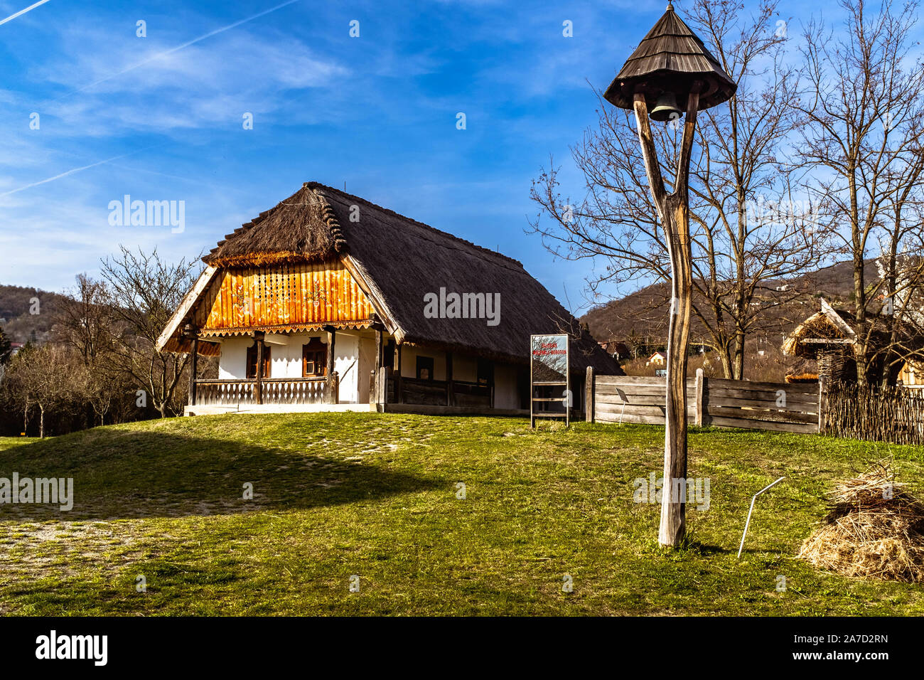 Traditional Hungarian house and a bell in Szentendre Skanzen Village Museum on a sunny spring day. Stock Photo