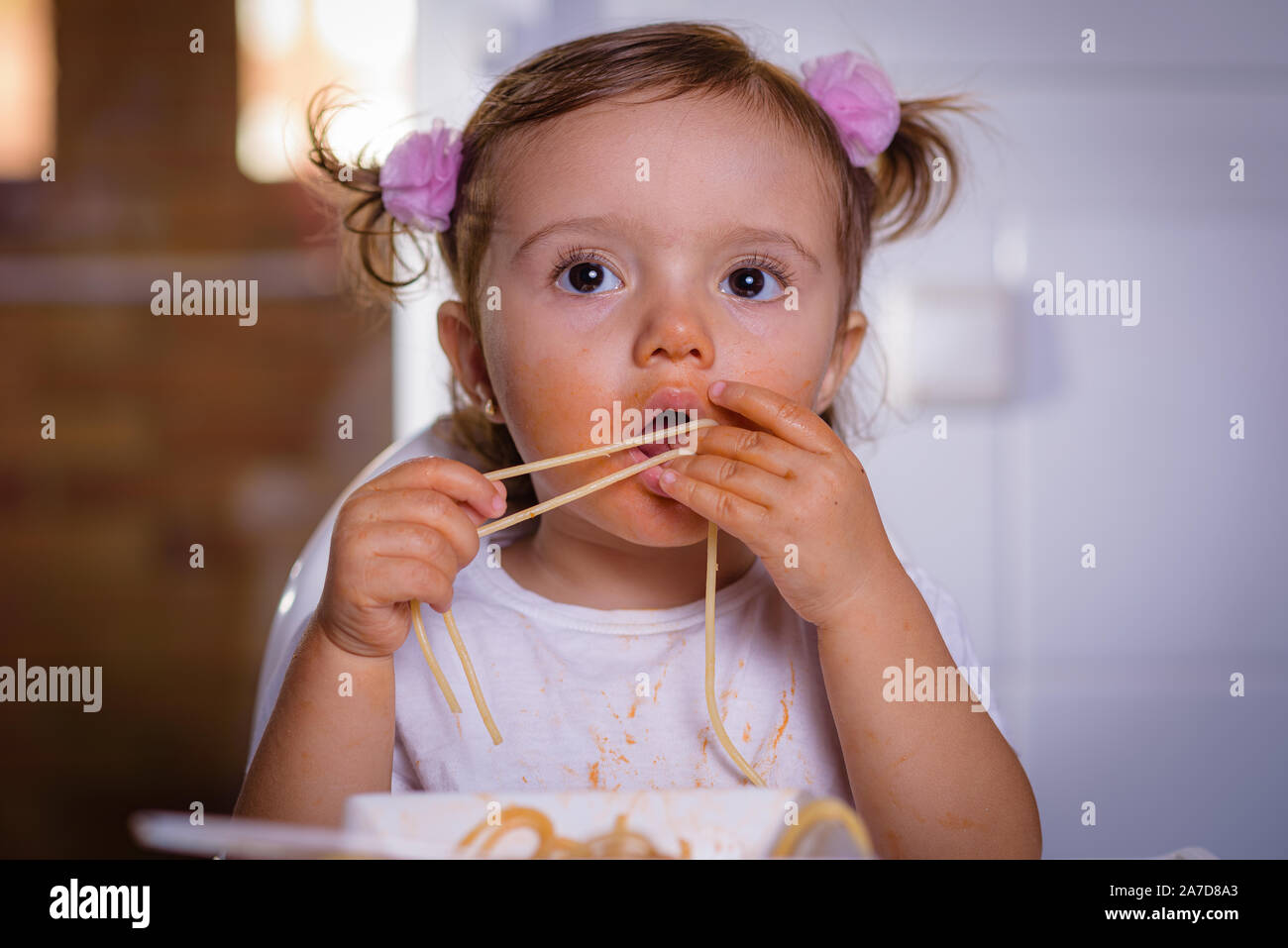 Adorable little girl eating spaghetti with Bolognese sauce with her