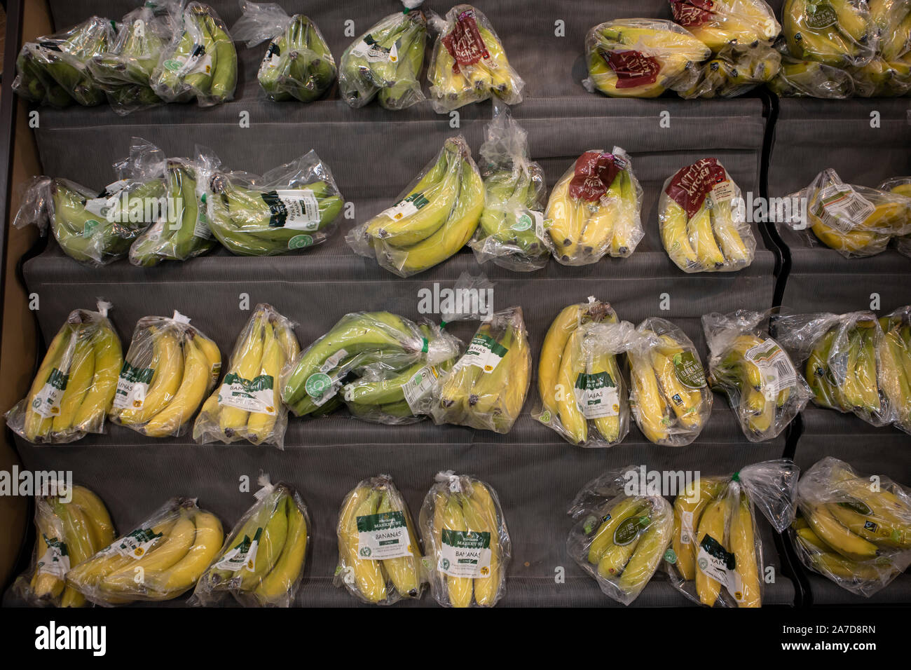 Bananas wrapped in plastic packaging being sold in a Morrisons supermarket, London, UK Stock Photo