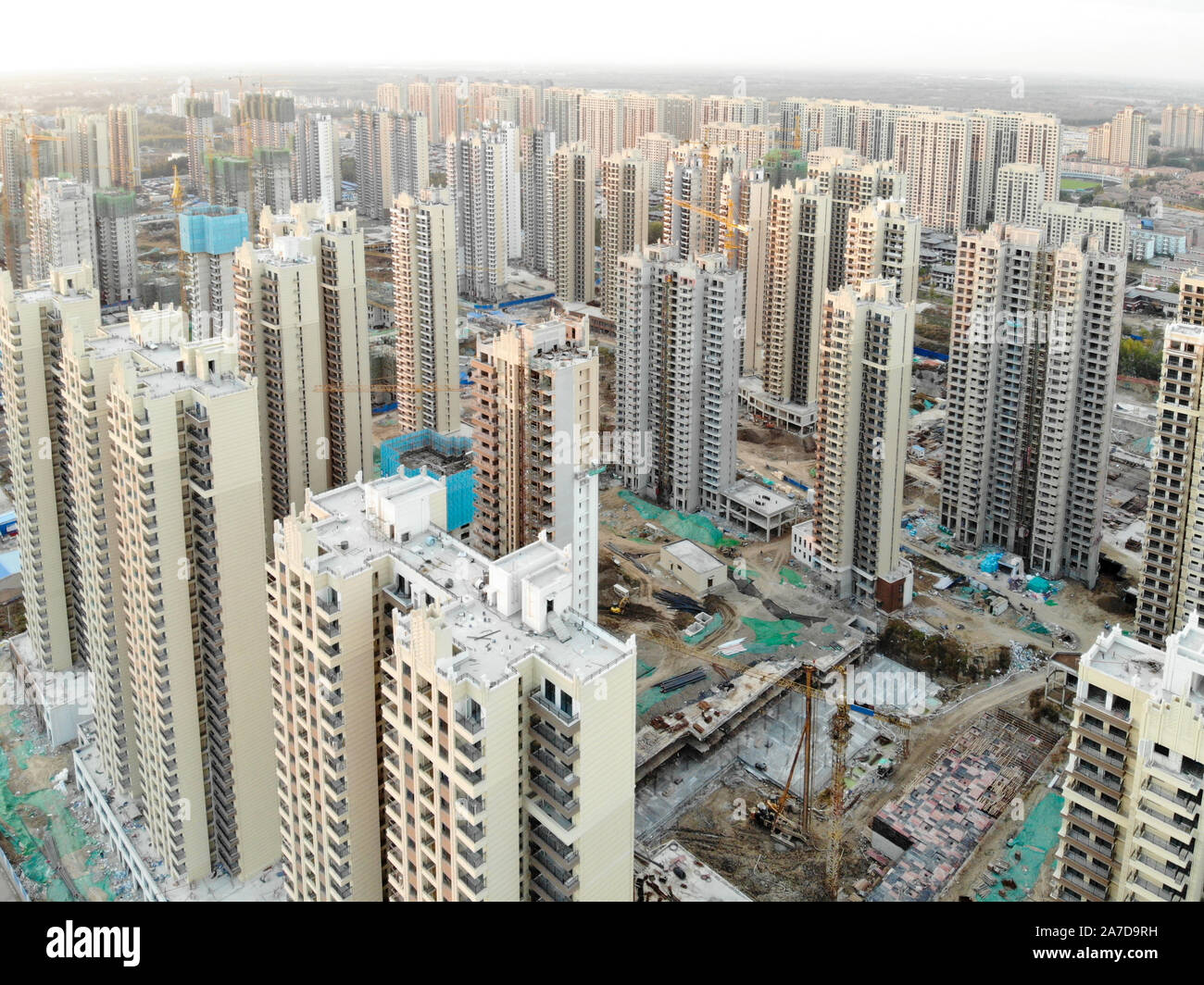 Aerial view of massive building sites in construction with tower crane. Building blocks apartment in construction in developing part of the city of Tianjin in China. Estate construction site. Stock Photo