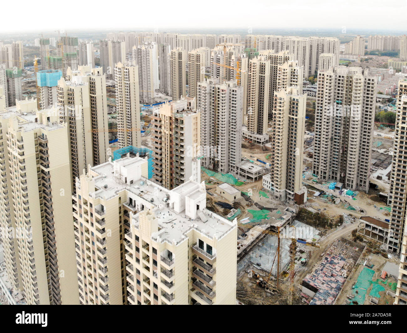 Aerial view of massive building sites in construction with tower crane. Building blocks apartment in construction in developing part of the city of Tianjin in China. Estate construction site. Stock Photo
