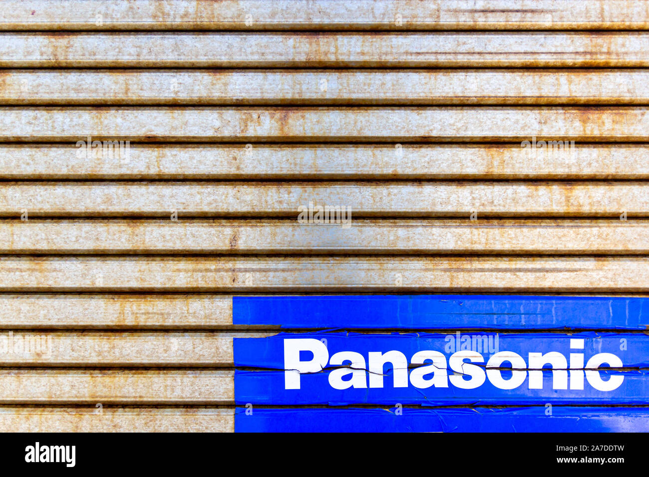 Panasonic sign (blue sticker) on rusty metal shutters Stock Photo