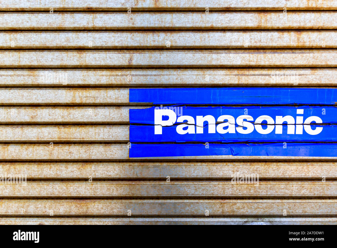 Panasonic sign (blue sticker) on rusty metal shutters Stock Photo