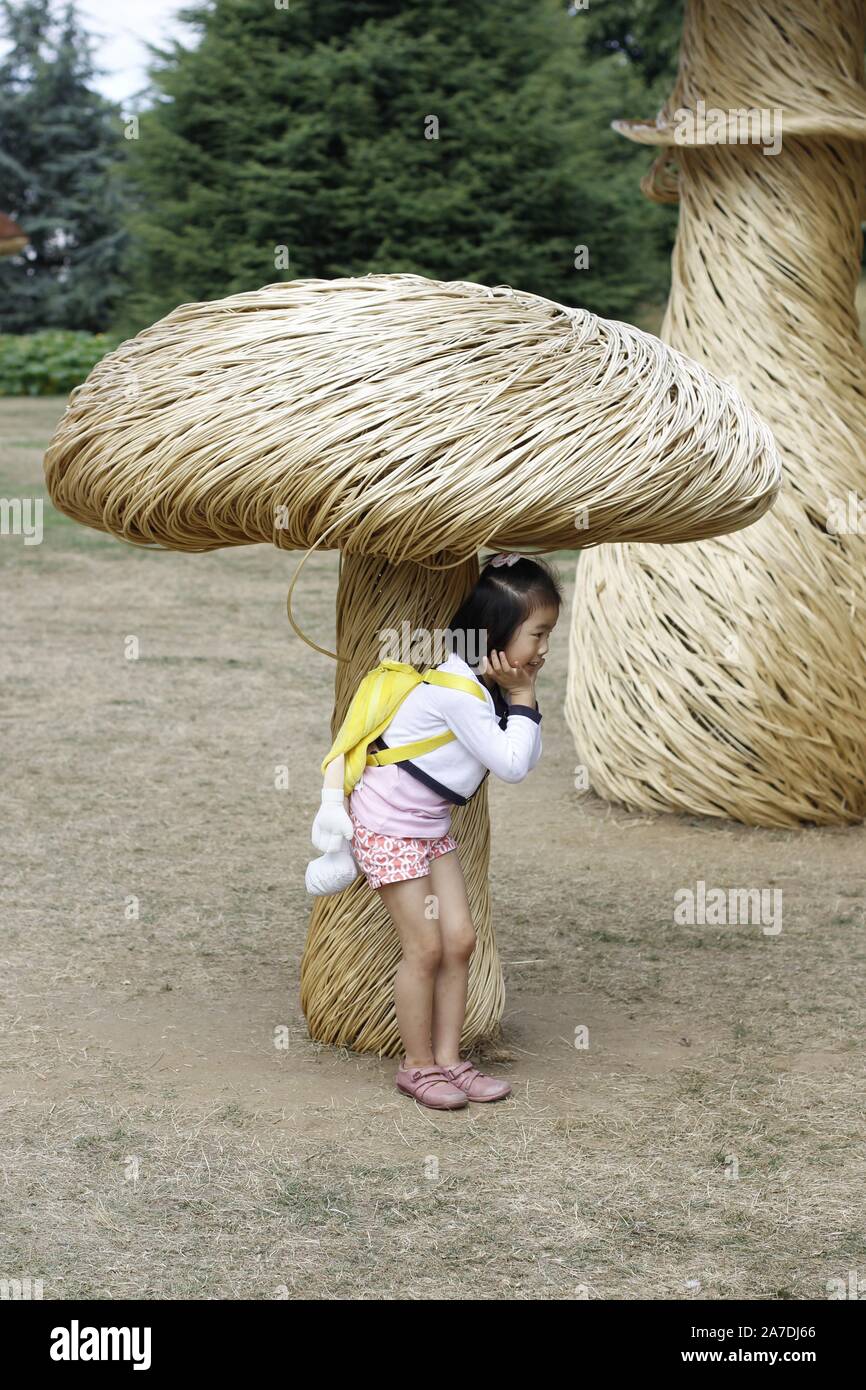 children playing under a giant man made mushroom or toadstool in a garden Stock Photo