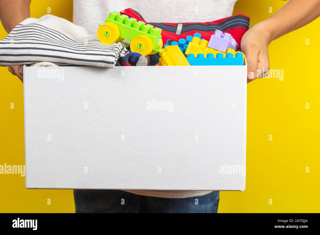Donation concept. Kid hands holding donate box with books, clothes and