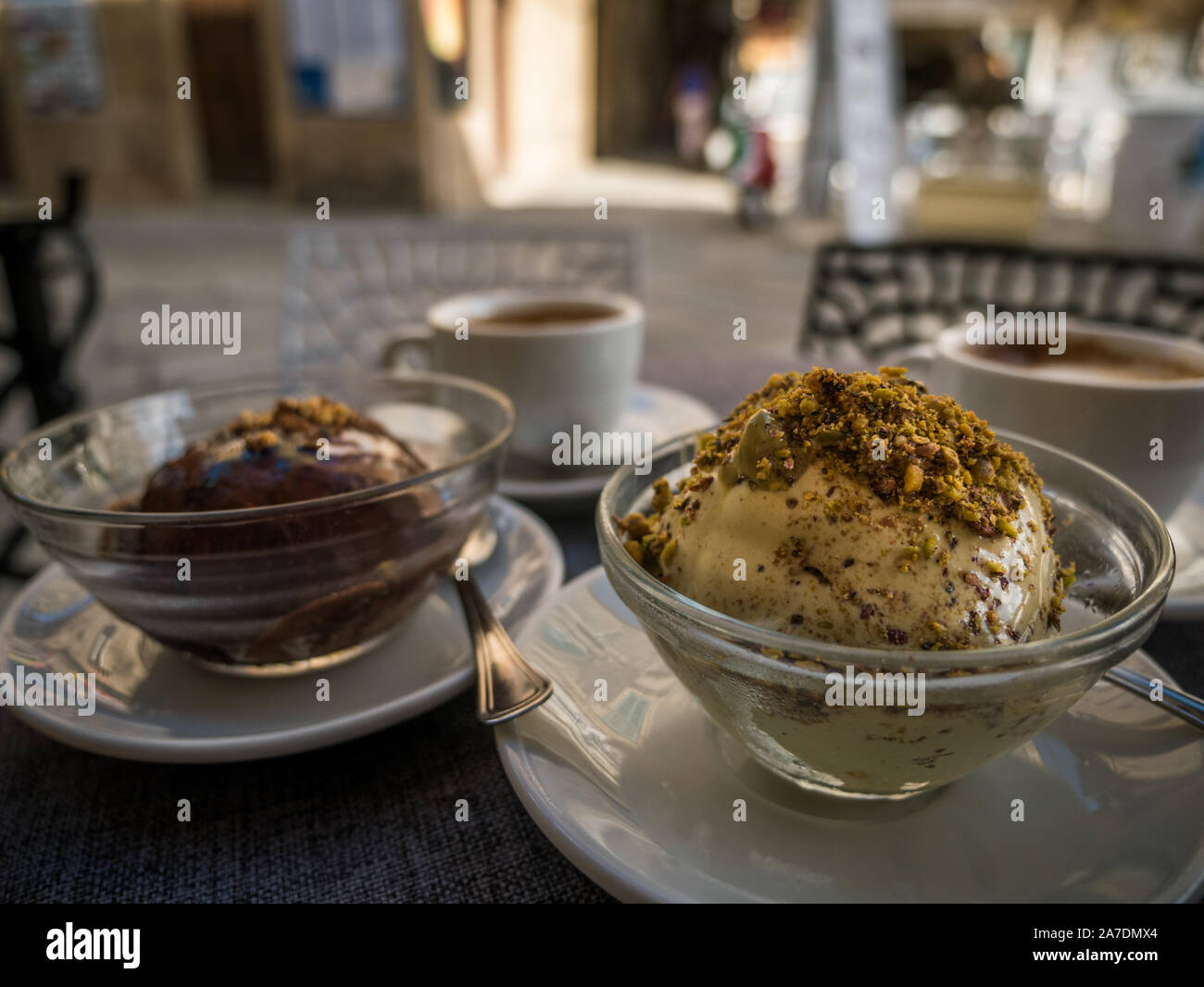Traditional Calabrian Tartufo ice creamin Tropea, chcocolate nougat and pistachio ice cream balls and coffee on a table infront of a cafe Stock Photo