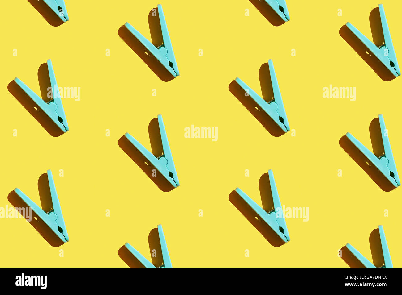 Blue clothespins pattern on yellow background, flatlay. Top view. Stock Photo