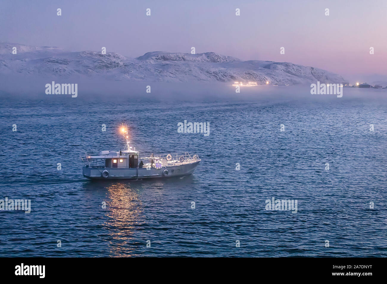 Small boat sails to port at sunset. Teriberka.  Barents sea. Kolsky District of Murmansk Oblast, Russia. Stock Photo
