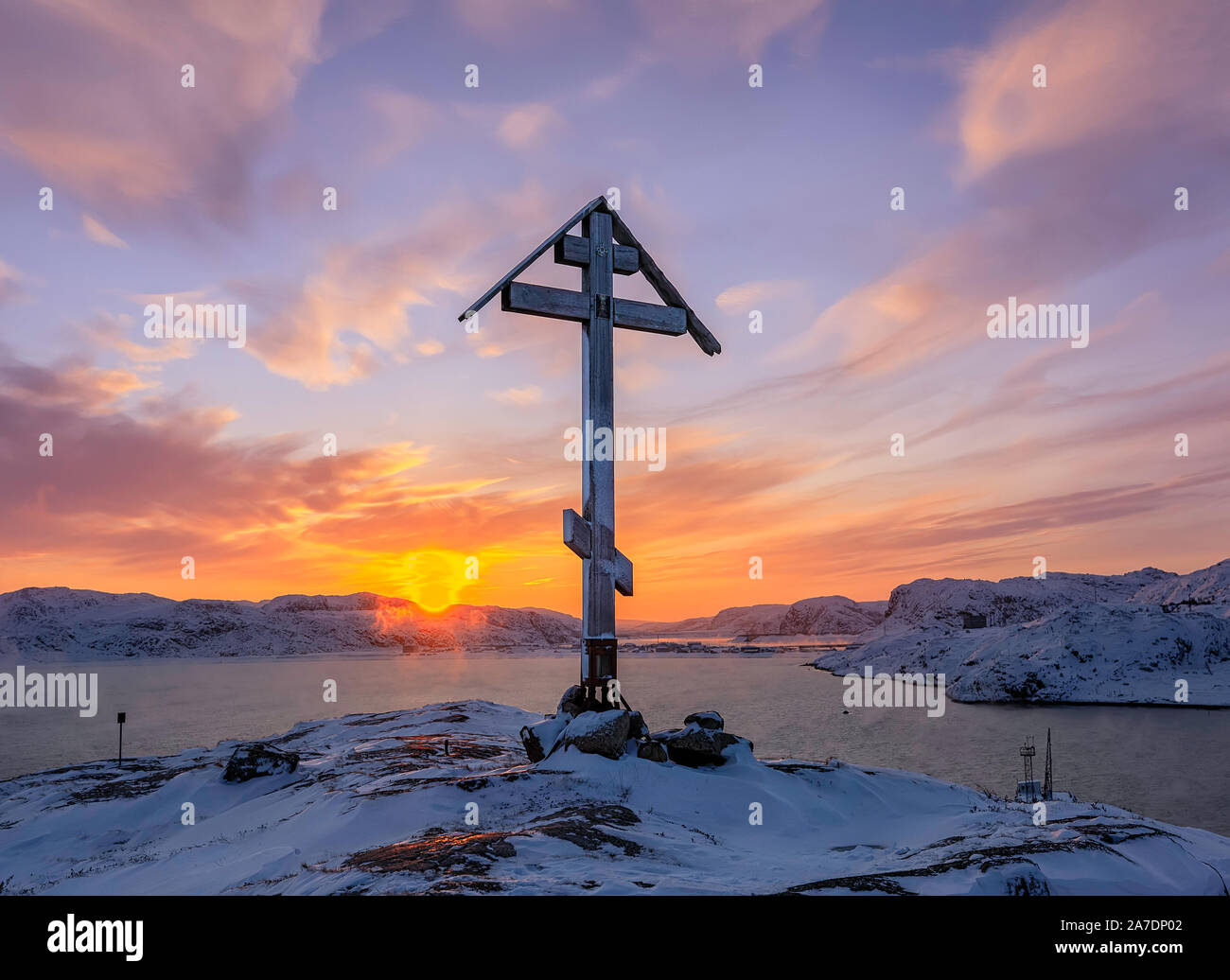 Orthodox cross on the top of the snow capped mountain at sunrise. Barents Sea coast at sunrise. Teriberka, Murmansk Region, Kola Peninsula. Russia Stock Photo