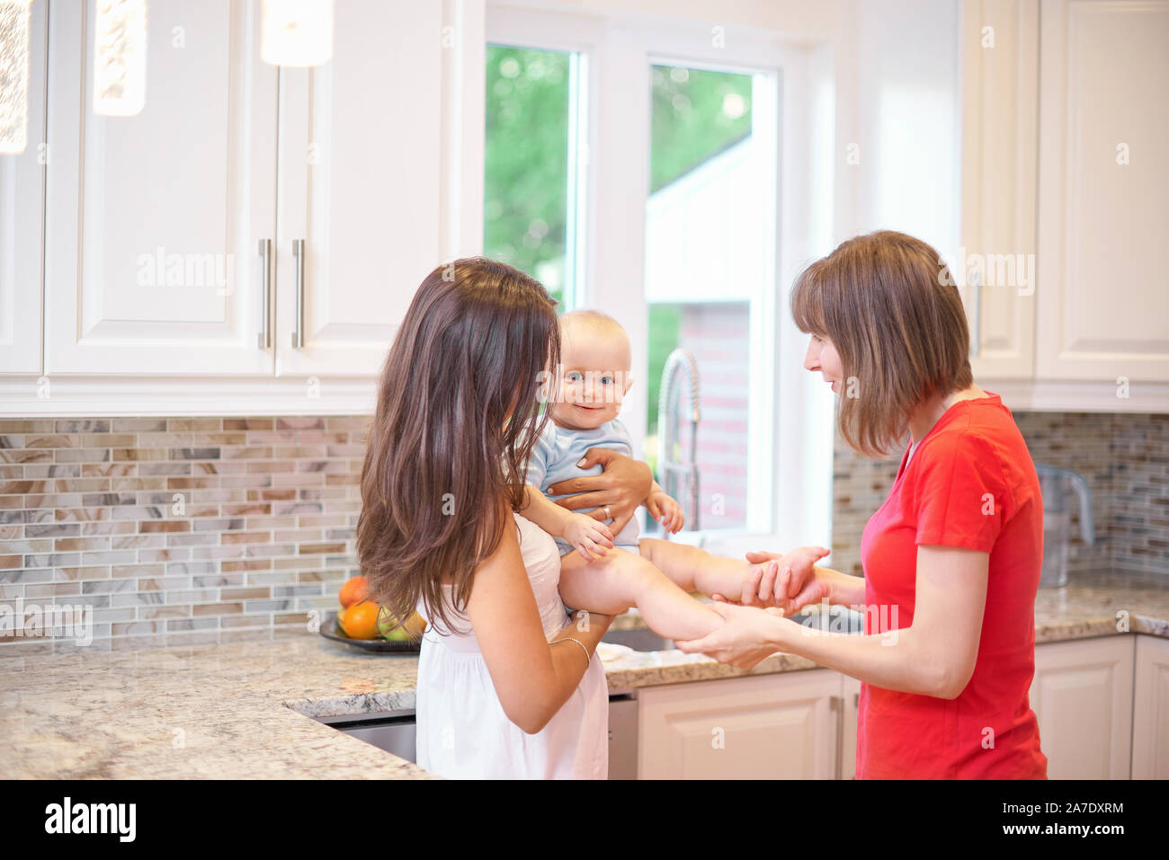 Young Mother Holds Her Baby Boy On Her Arms And Shows Him How To Adjusts  The Temperature Of The Household On A Thermostat In The Kitchen High-Res  Stock Photo - Getty Images