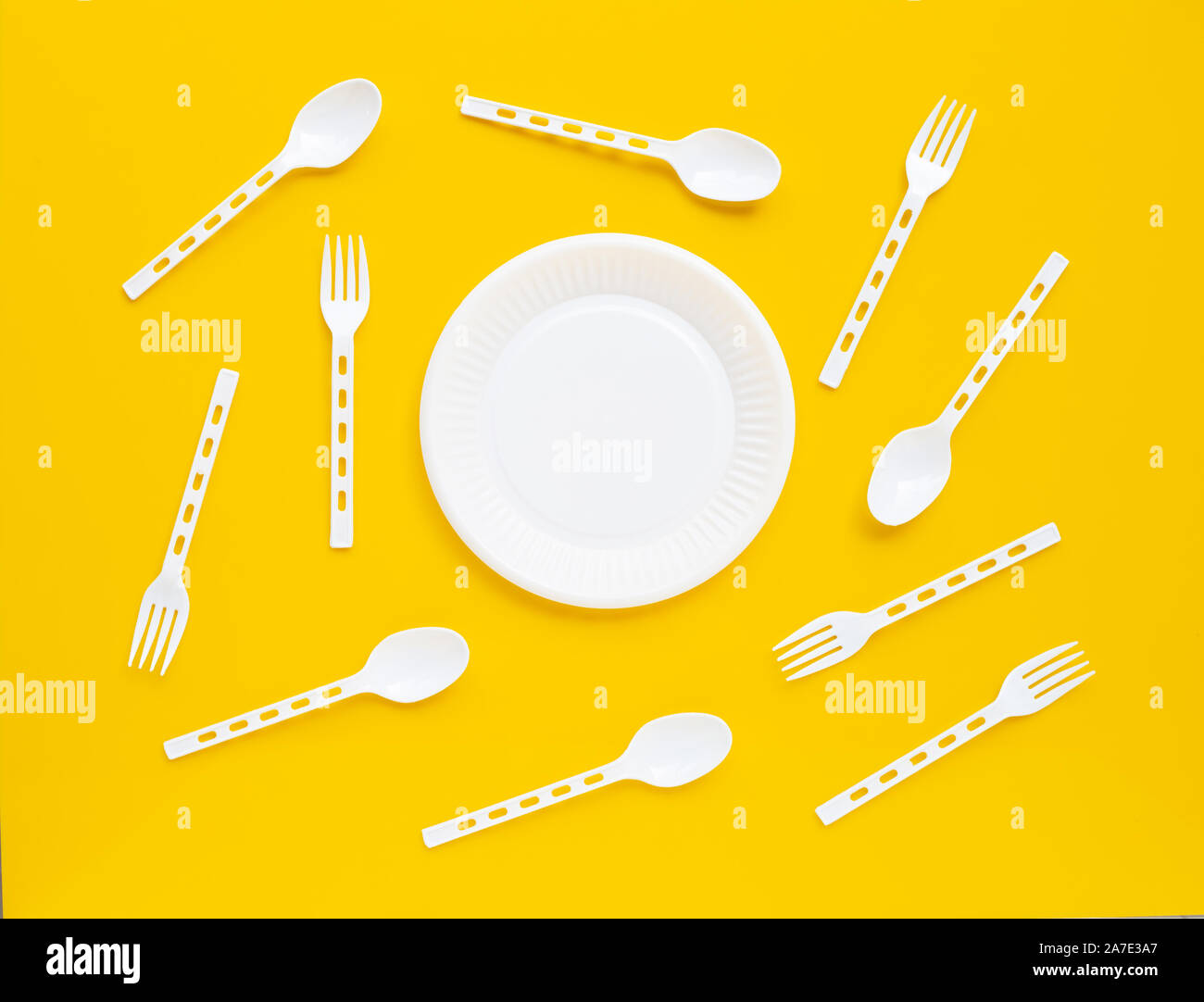 Plastic dish, spoon and fork on yellow background. Stock Photo