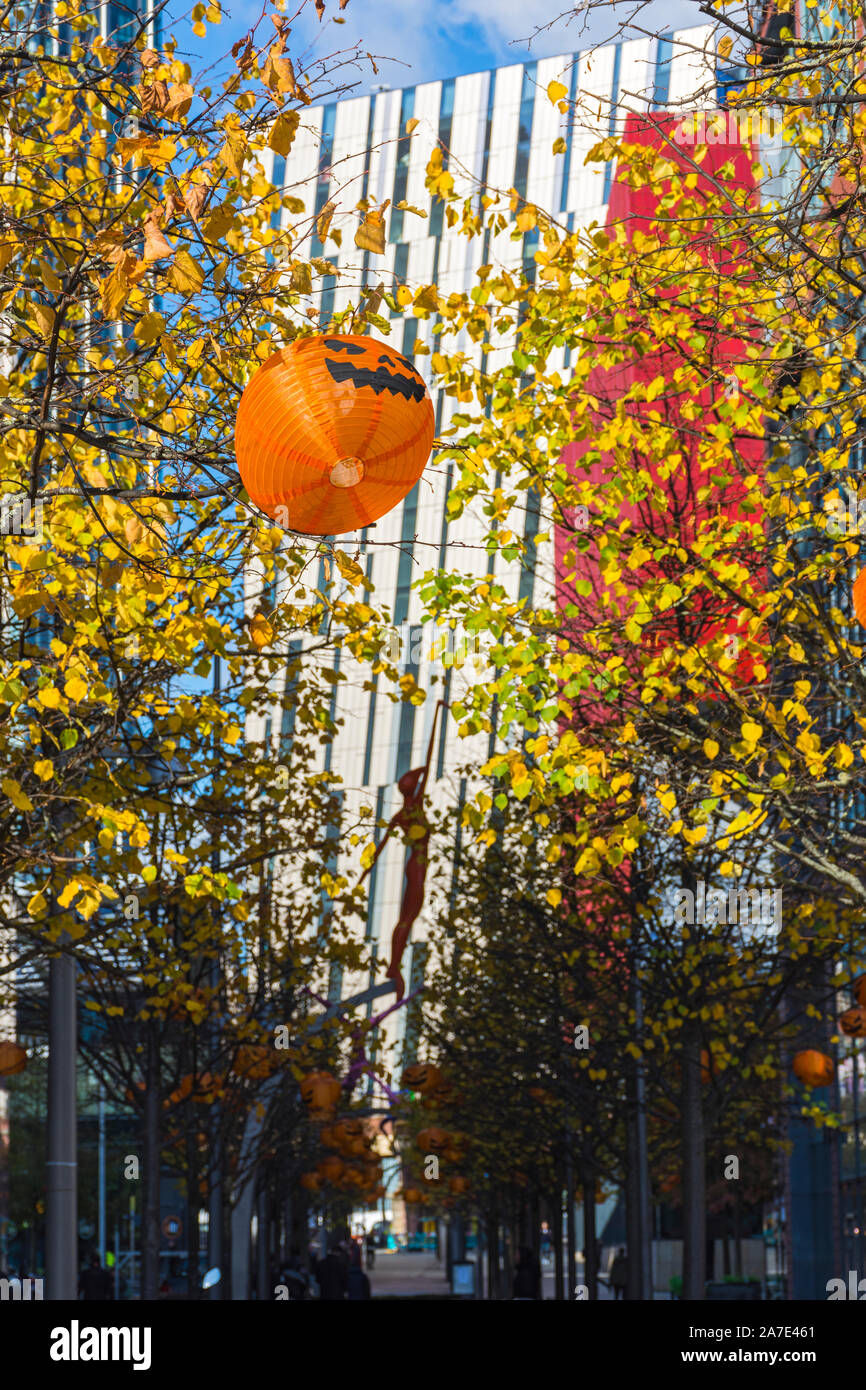 Paper lantern in the shape of a Halloween pumpkin head, First Street, Manchester, England, UK. The Axis Tower behind. Stock Photo