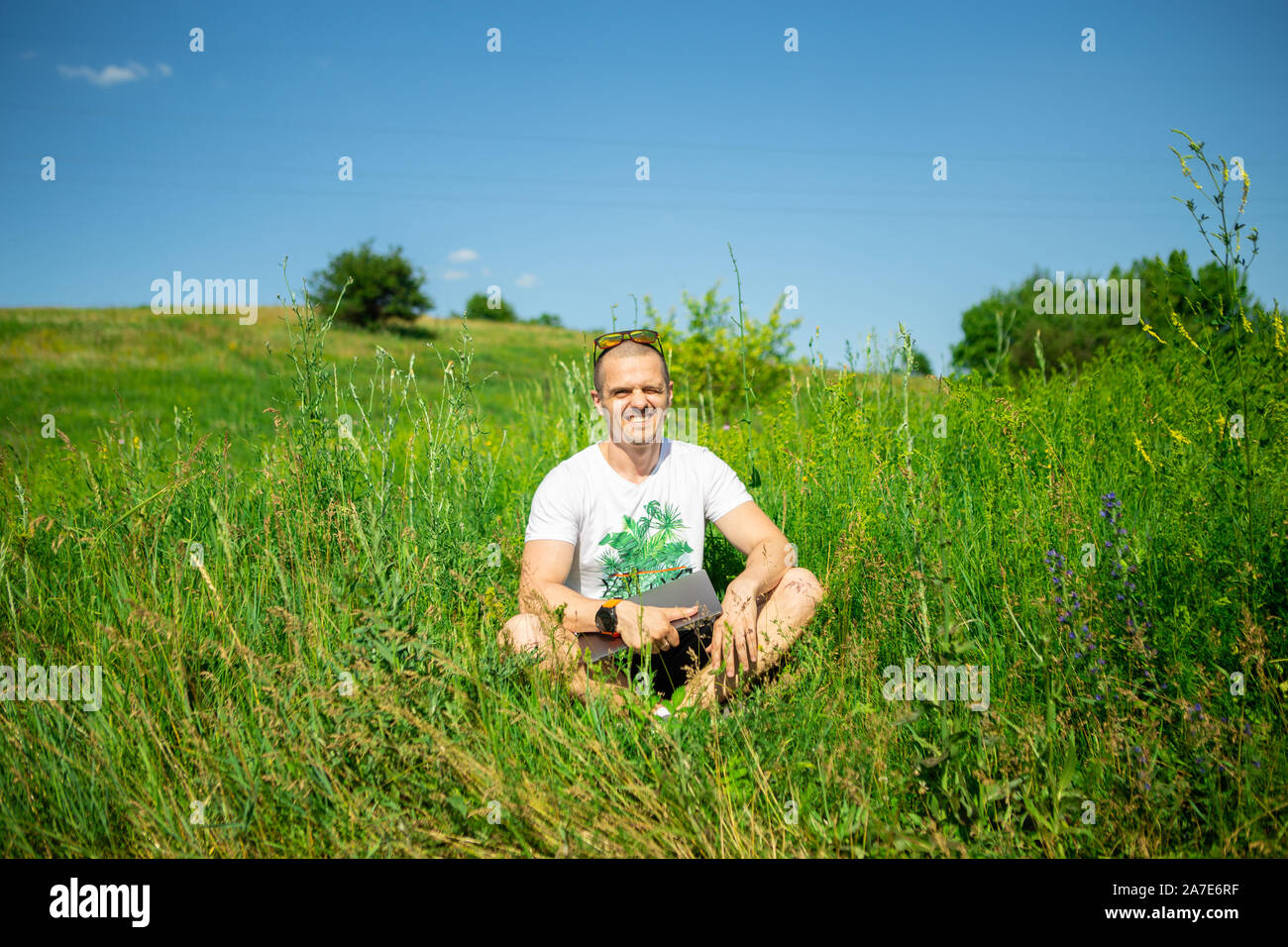 Man freelancer sitting on grass with laptop Stock Photo