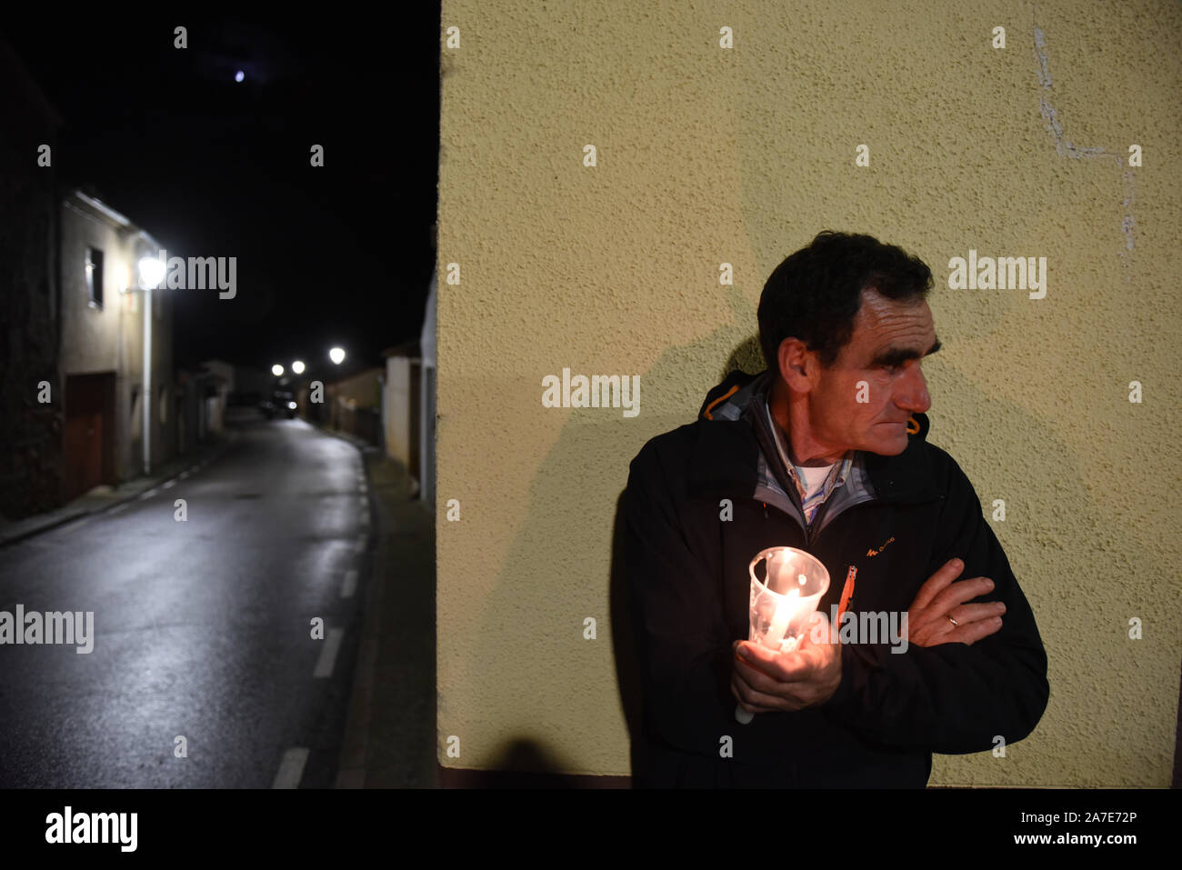 A man holds a candle at the side of the street during the festival.Dozens of men of Tanjueco north of Spain gathered on the streets of this small village during the celebrations of All Saint's Day. Villagers divided into two groups: single and married, sang 'Cantos de las Ánimas' (Songs of Souls) to accompany the souls during their 'way' from Purgatory to the Heaven. It is a medieval and unique tradition around the world. Stock Photo
