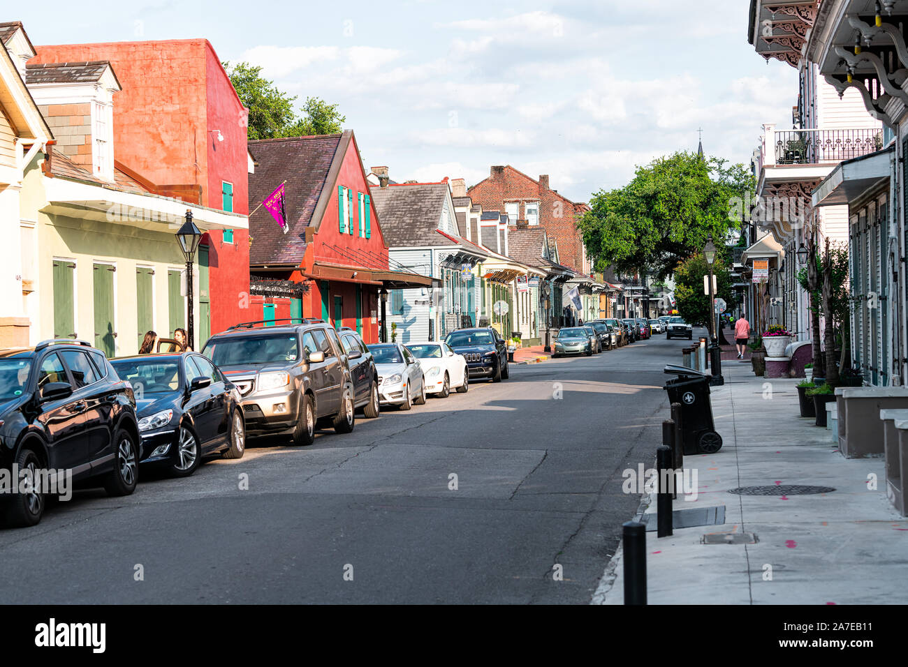 New Orleans, USA - April 23, 2018: Old town Orleans street sidewalk in Louisiana famous town with row of red colorful buildings homes and parked cars Stock Photo