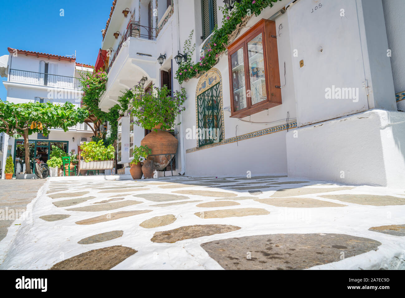 SKIATHOS GREECE - JULY 30 2019; Crazy paving leading past large terra cotta urn to green chairs. Stock Photo