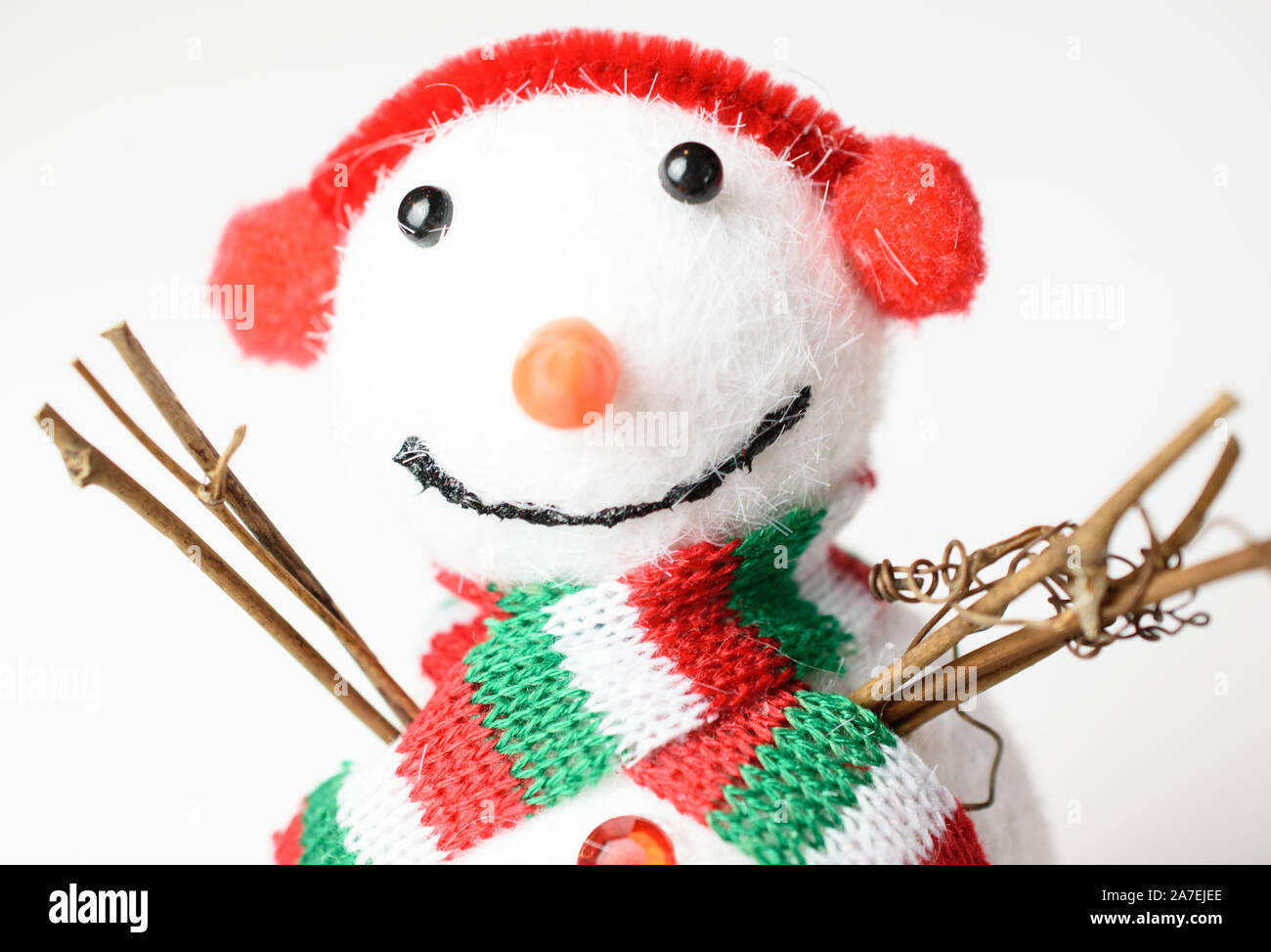 Closeup of adorable snowman wearing a red white and green scarf and earmuffs Stock Photo