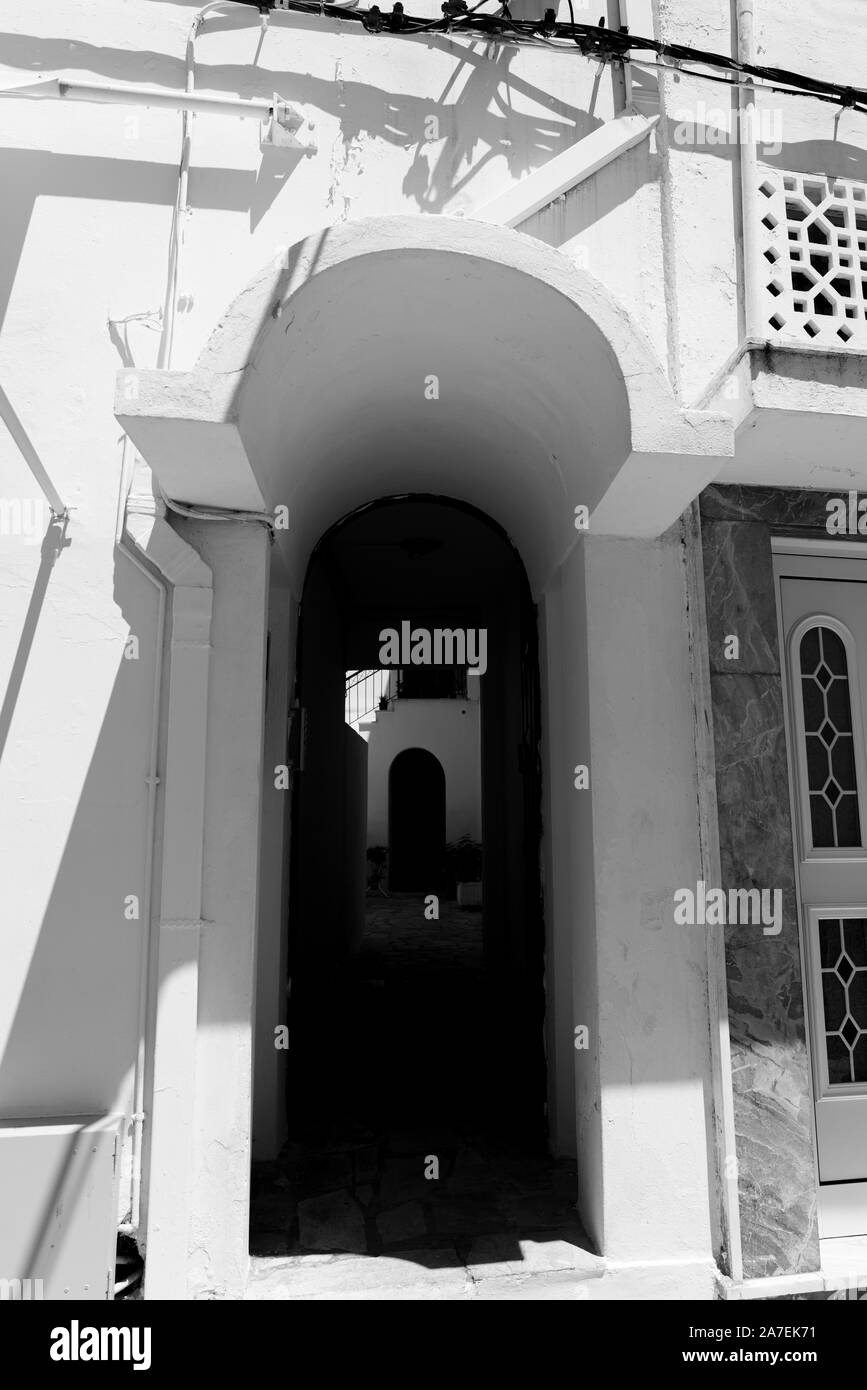Stucco architectural arch over entrance and corridor in black and white vertical composition. Stock Photo