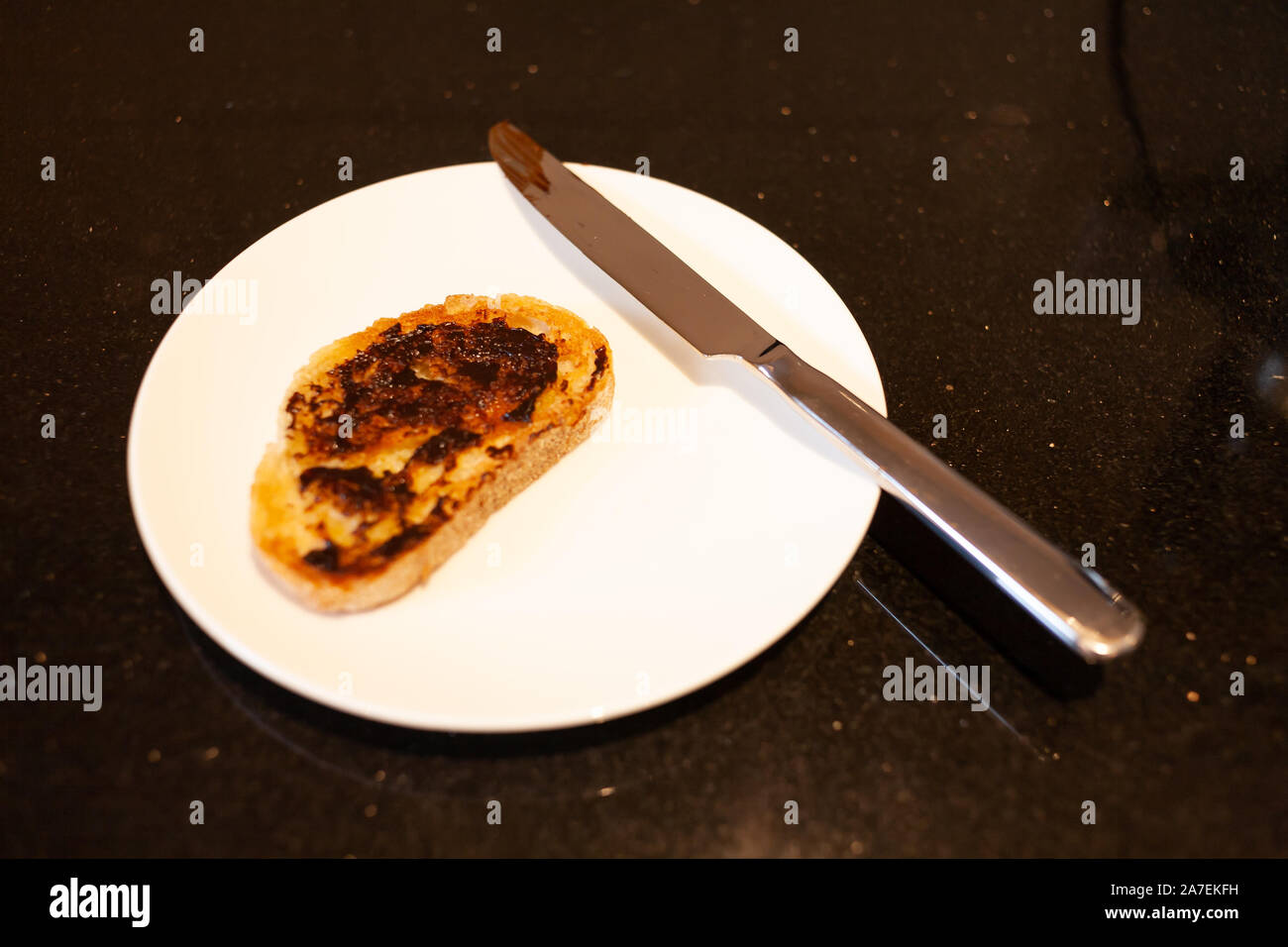 Vegemite and butter on sourdough toast with knife on Kitchen bench. An