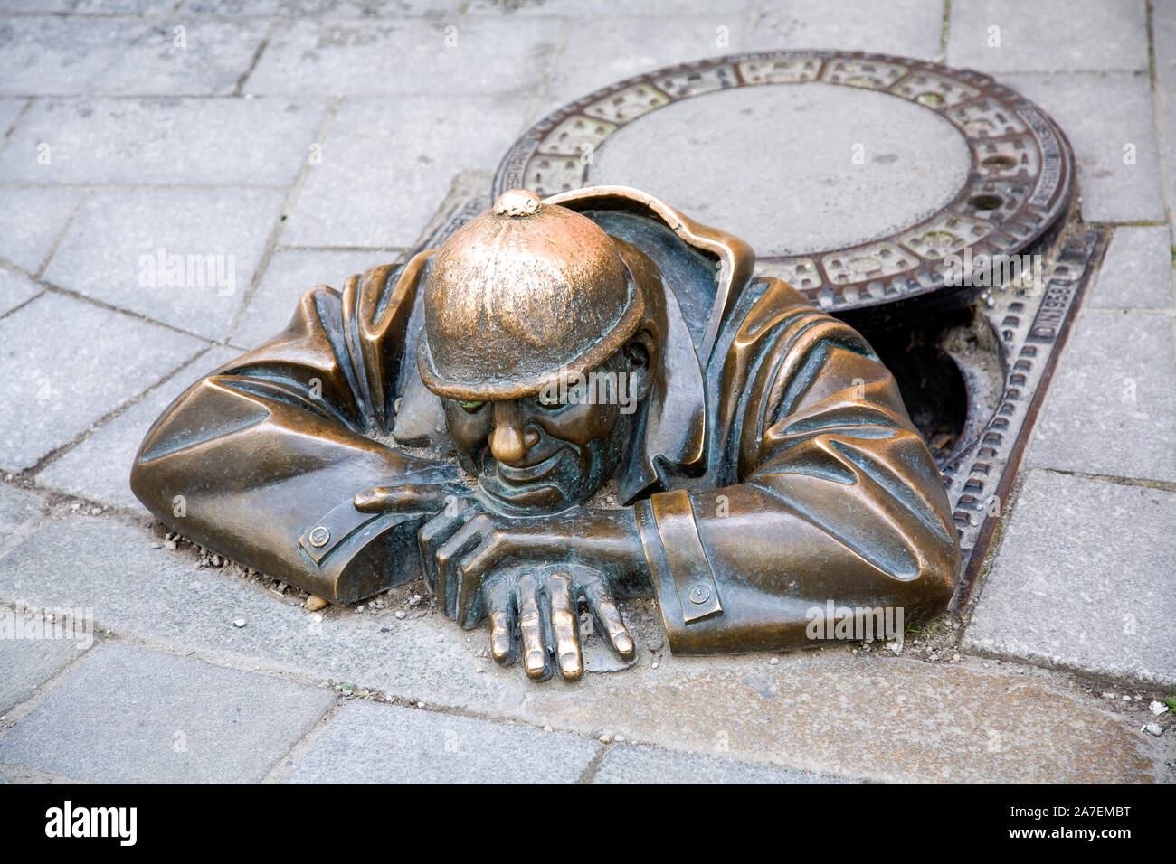 Street art in the form of a bronze statue called The Watcher who appears out of an imaginary manhole in Bratislava Slovakia Stock Photo
