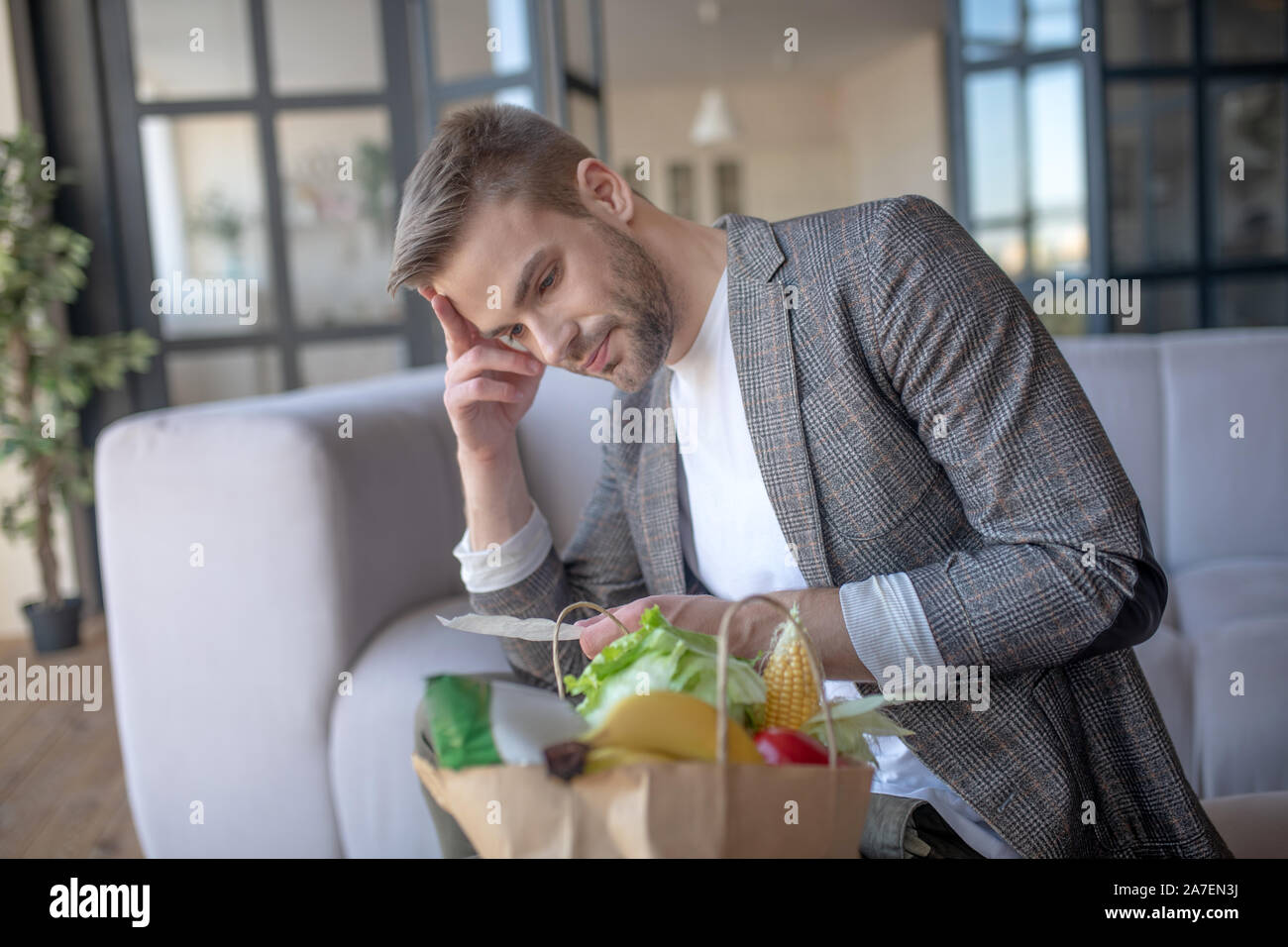 Bearded man looking at receipt and checking prices Stock Photo