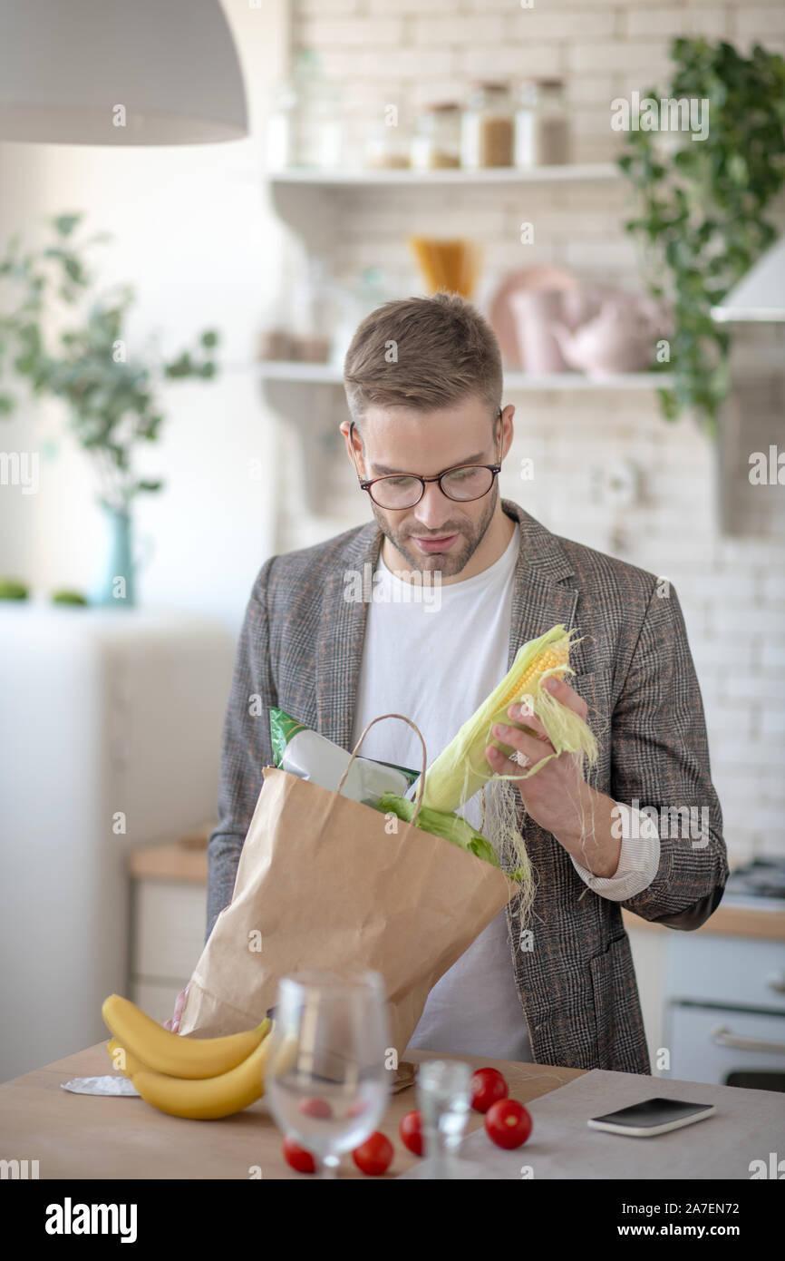Man taking corn out of bag after going to supermarket Stock Photo