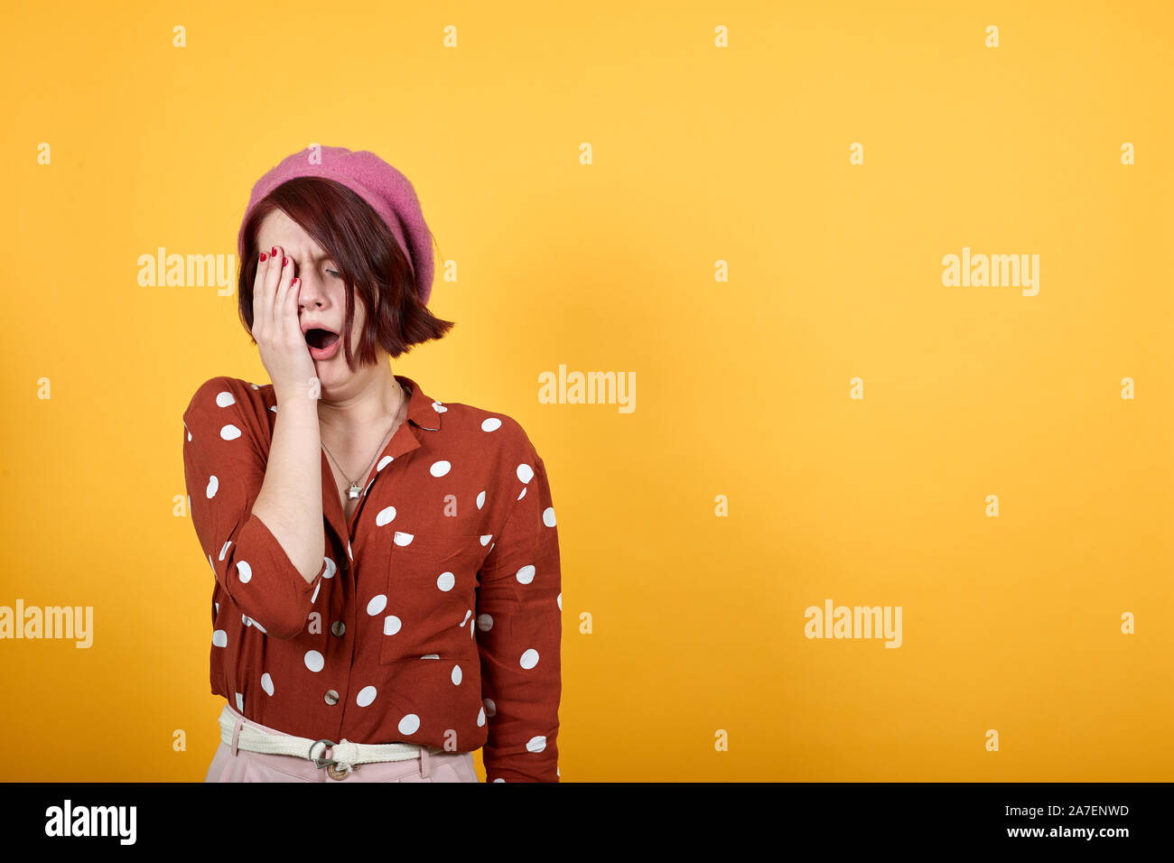 Tired young caucasian yawning looks bored, covering half face with hand. Stock Photo