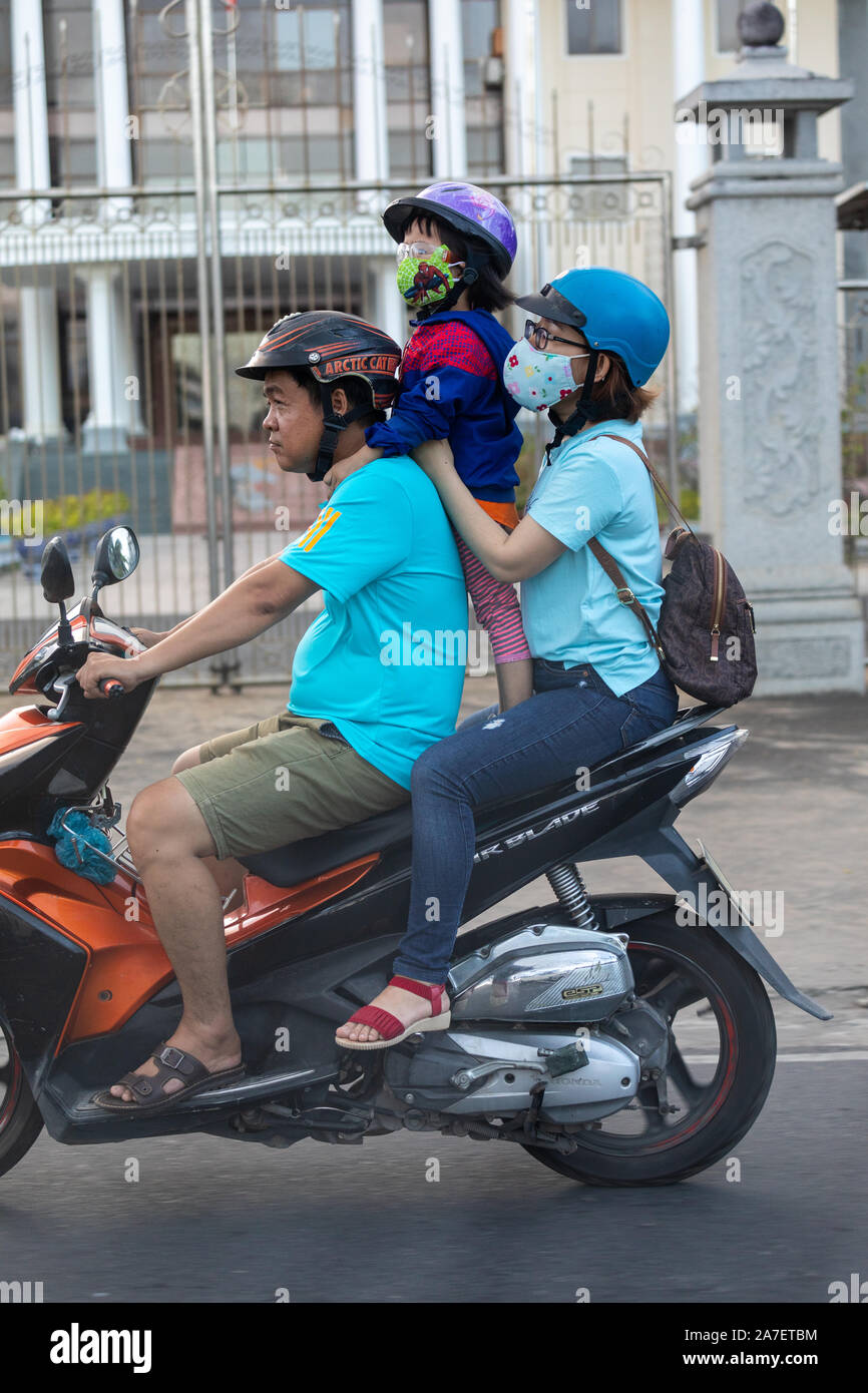 Vietnam, Nha Trang city, March 25, 2019. a Vietnamese family rides on a motorbike together. The child and his mother are wearing a protective face mas Stock Photo