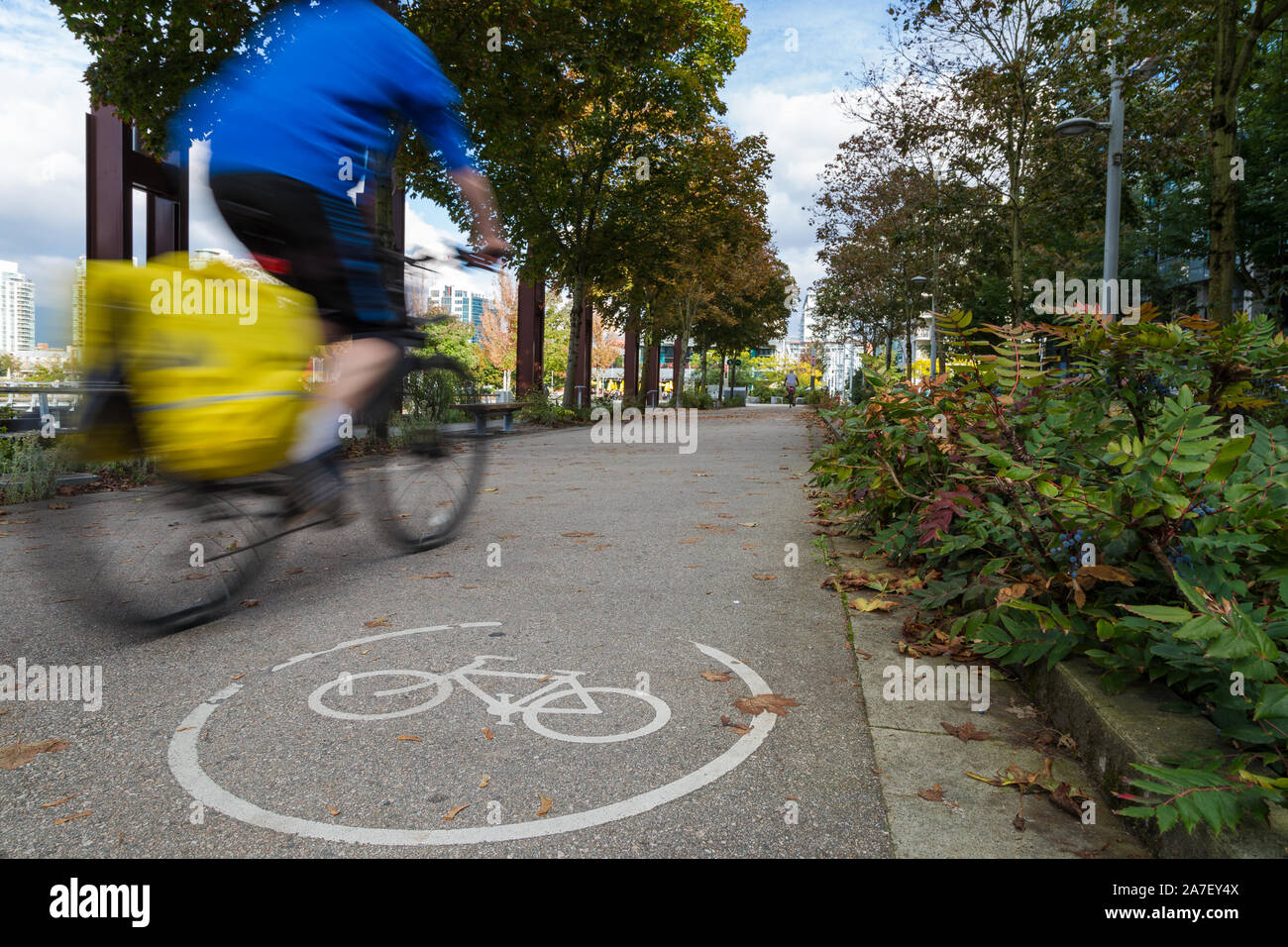 An urban bike route and a cyclist motion blurred travelling past in Olympic Village Vancouver. Stock Photo