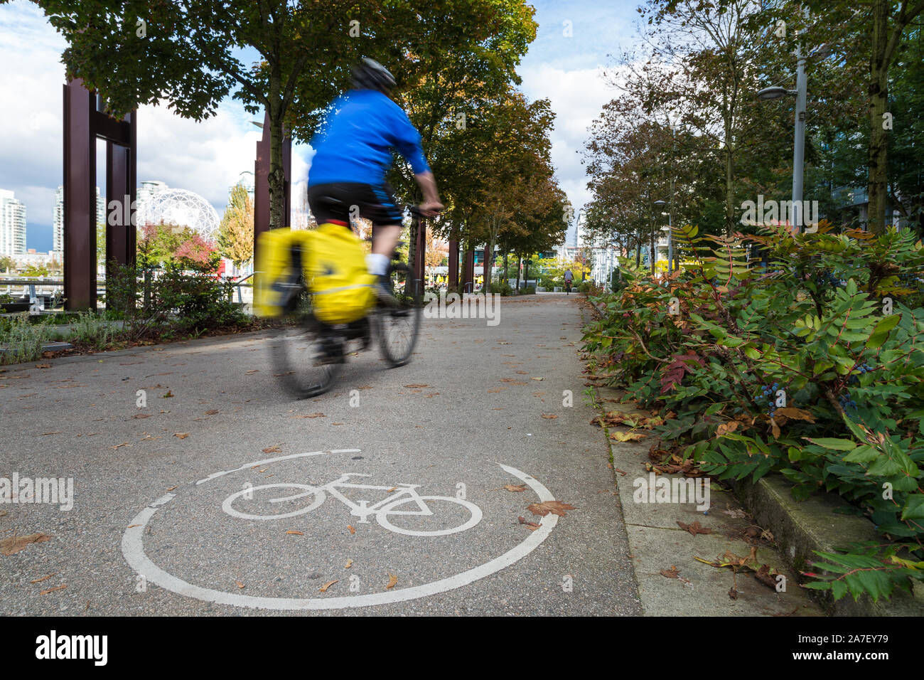 An urban bike route and a cyclist motion blurred travelling past in Olympic Village Vancouver. Stock Photo
